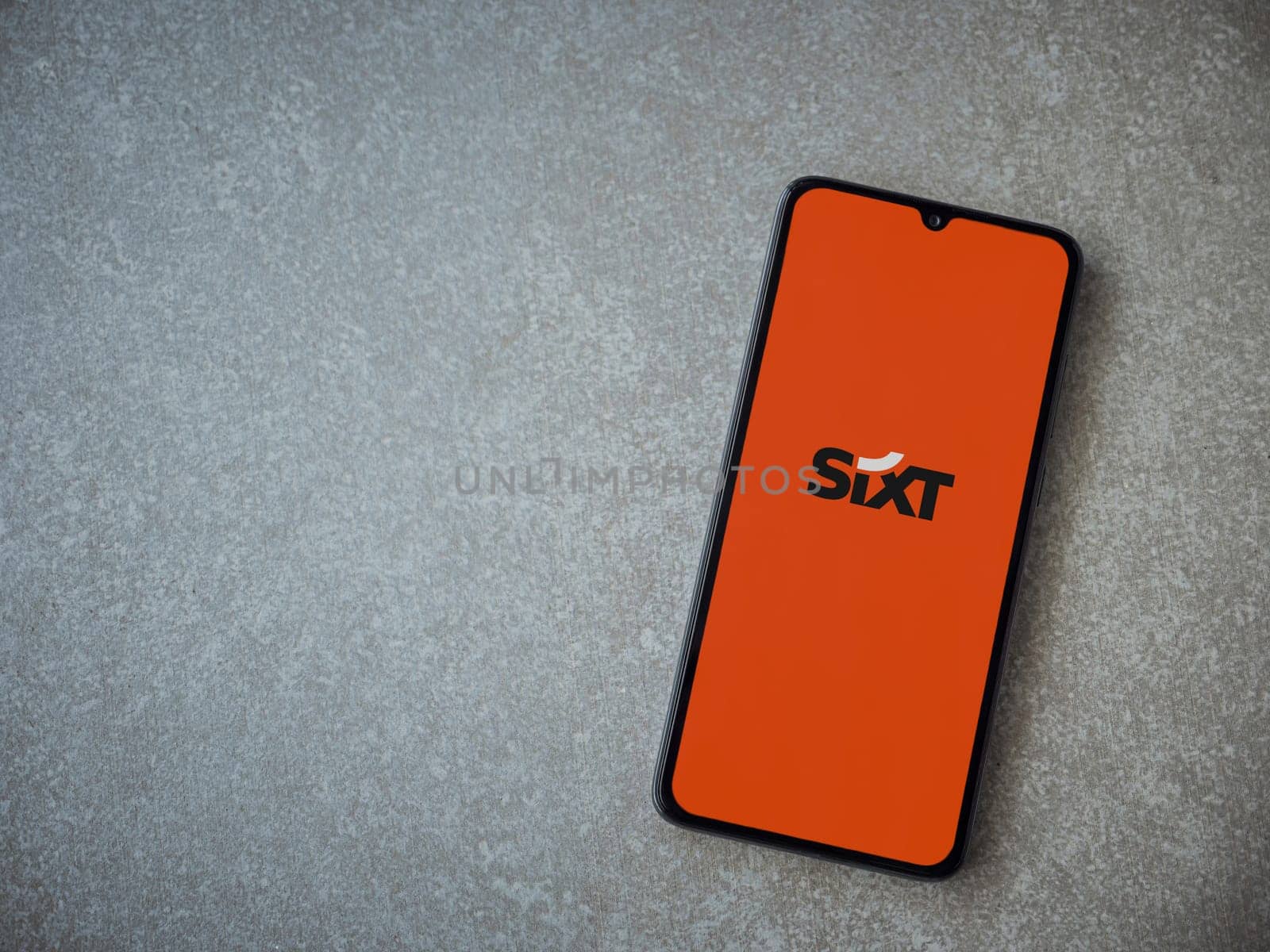 Lod, Israel - July 16,2023: SIXT rent app launch screen on smartphone on ceramic stone background. Top view flat lay with copy space.