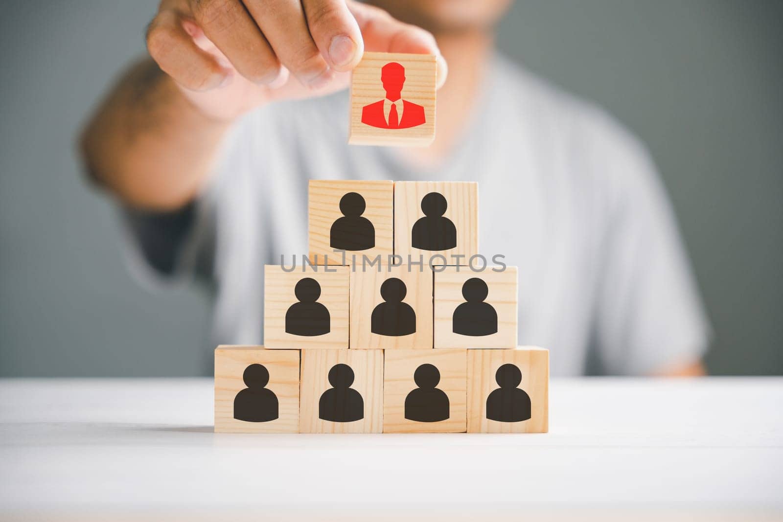 Stock photo illustrating human resources talent management and recruitment. Person icons on wooden cube block symbolize teamwork and organization. Woman leadership concept in a business setting.