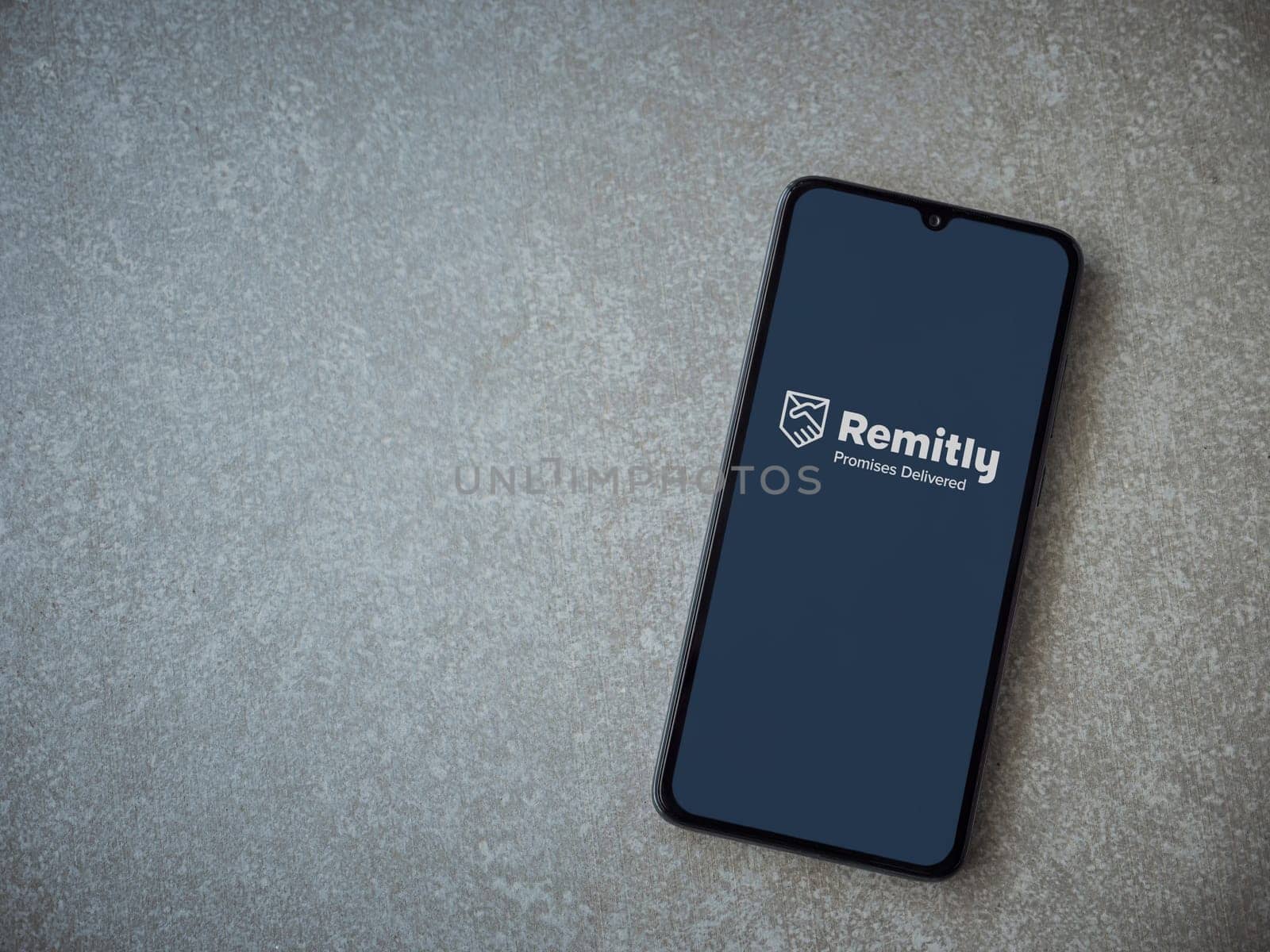 Lod, Israel - July 16,2023: Remitly app launch screen on smartphone on ceramic stone background. Top view flat lay with copy space.