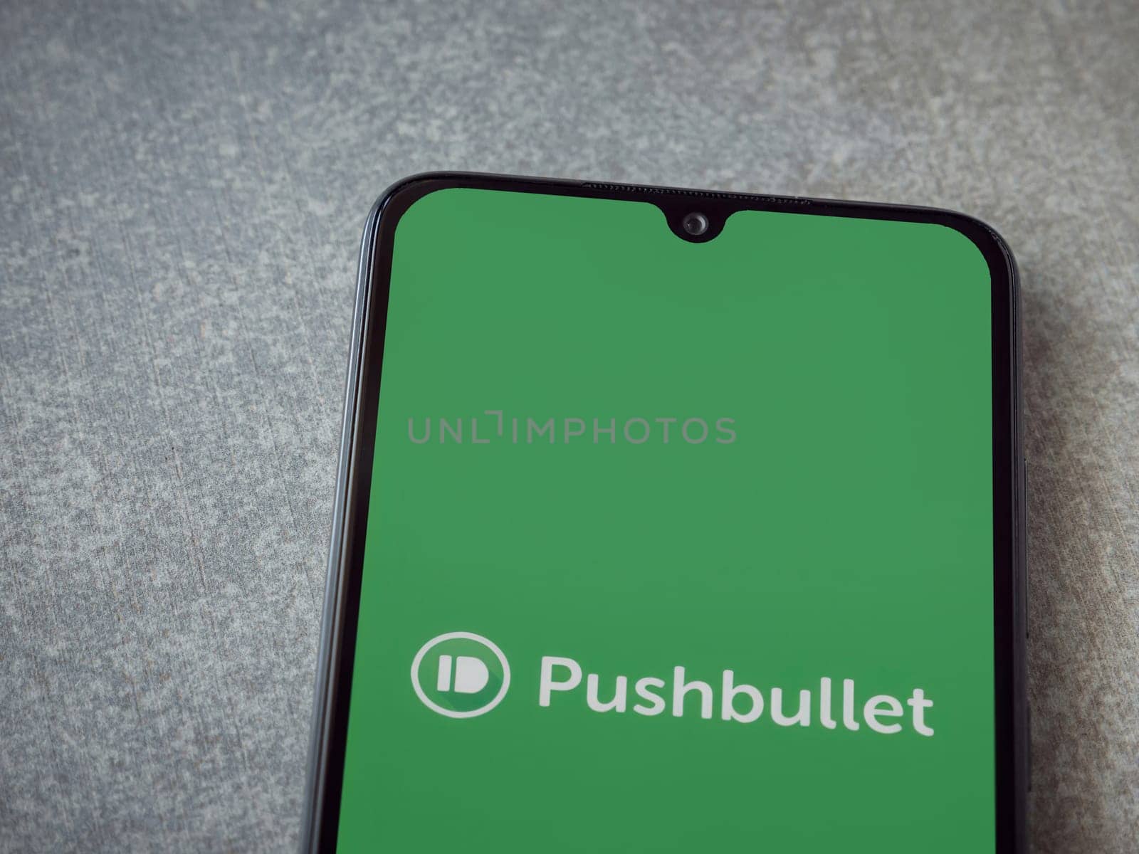 Lod, Israel - July 16,2023: Pushbullet app launch screen on smartphone on ceramic stone background. Top view flat lay with copy space.