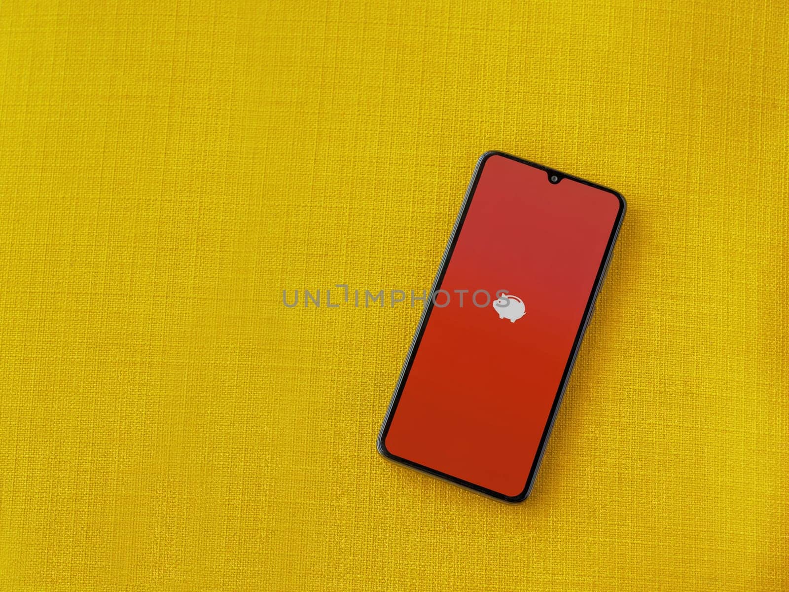 Lod, Israel - July 16,2023: Money Manager Expense & Budget app launch screen on smartphone on yellow fabric background. Top view flat lay with copy space.