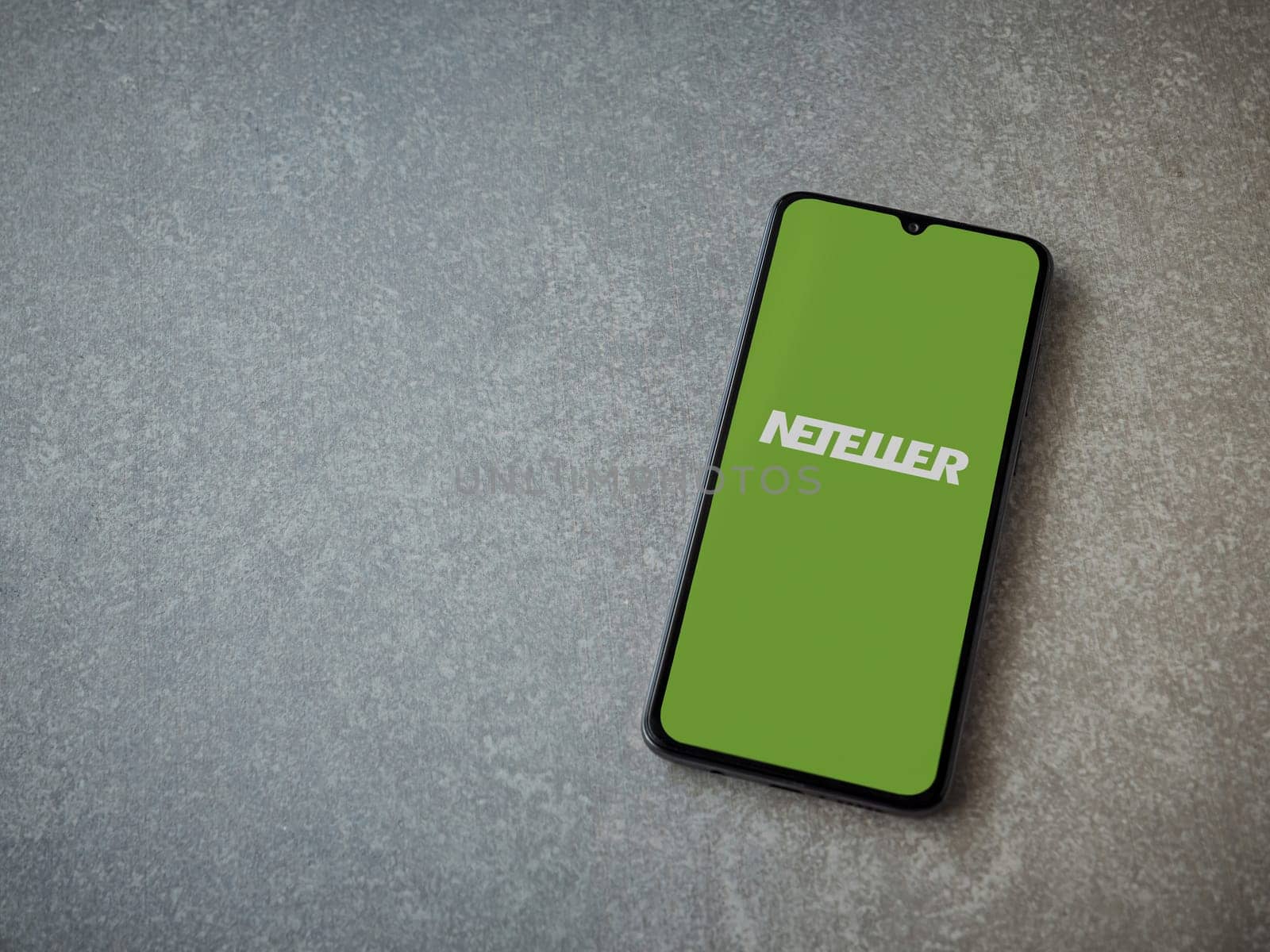 Lod, Israel - July 16,2023: NETELLER app launch screen on smartphone on ceramic stone background. Top view flat lay with copy space.