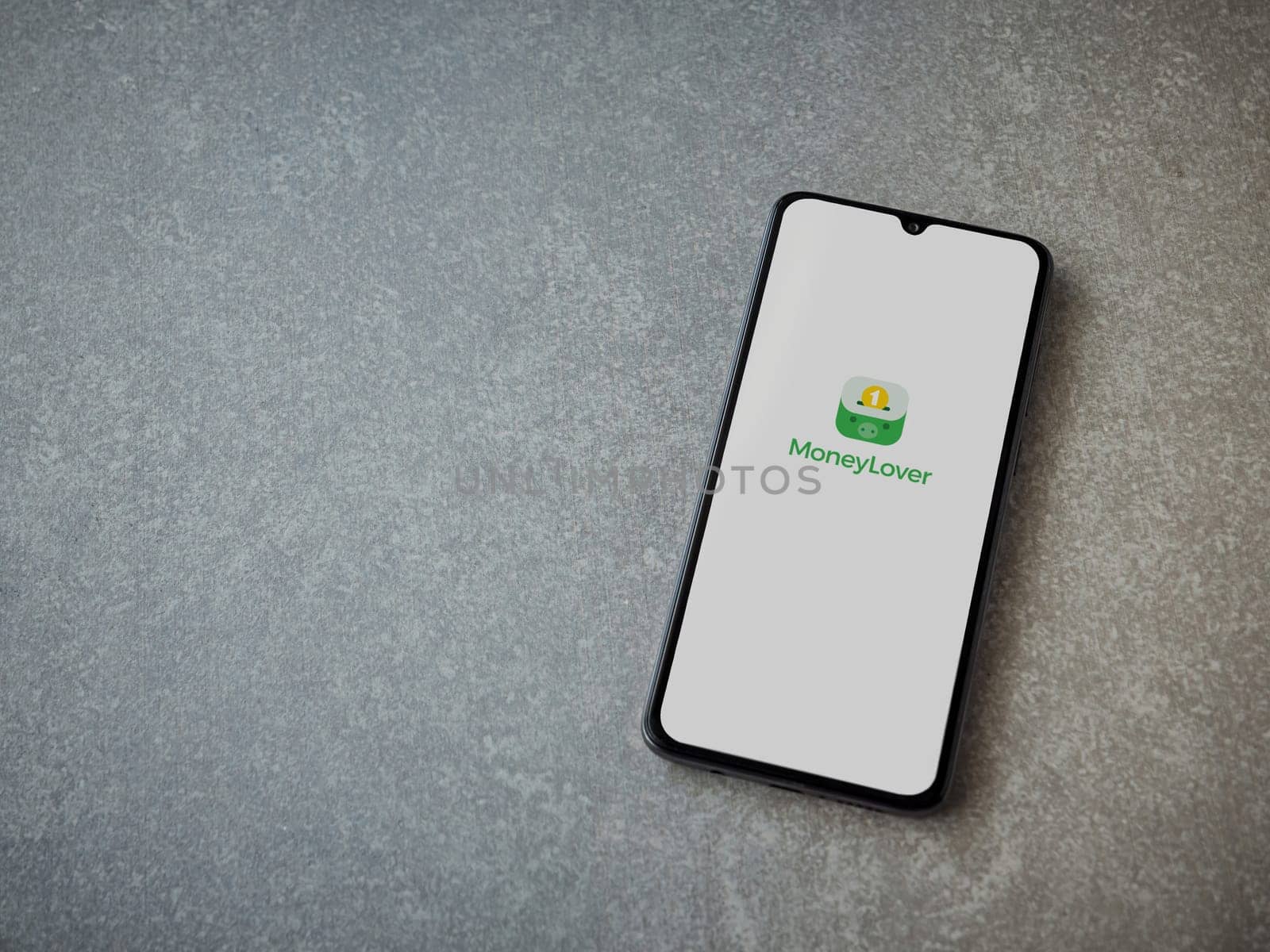 Lod, Israel - July 16,2023: Money Lover app launch screen on smartphone on ceramic stone background. Top view flat lay with copy space.