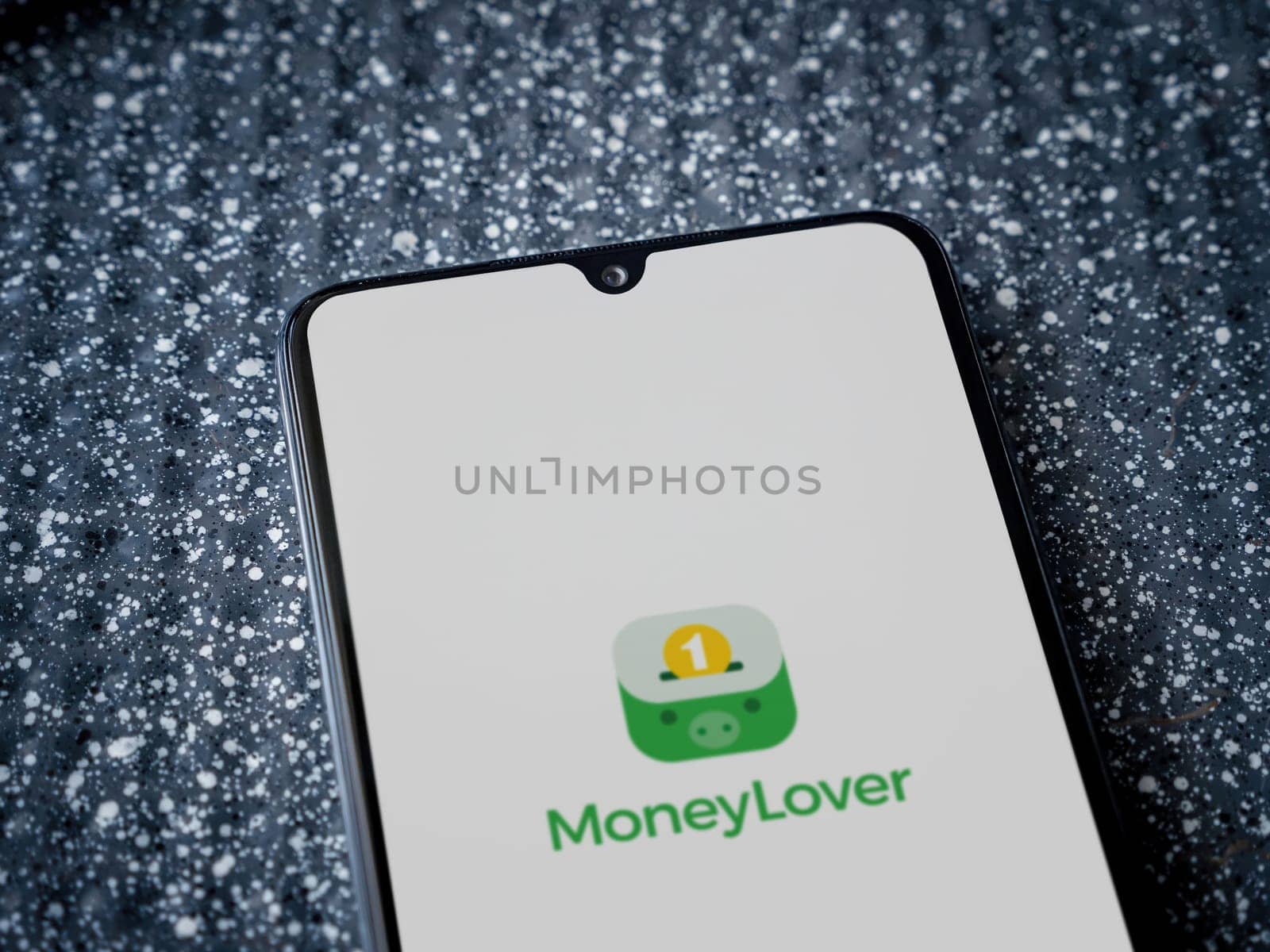 Lod, Israel - July 16,2023: Money Lover app launch screen on smartphone on metallic background. Close up top view flat lay.