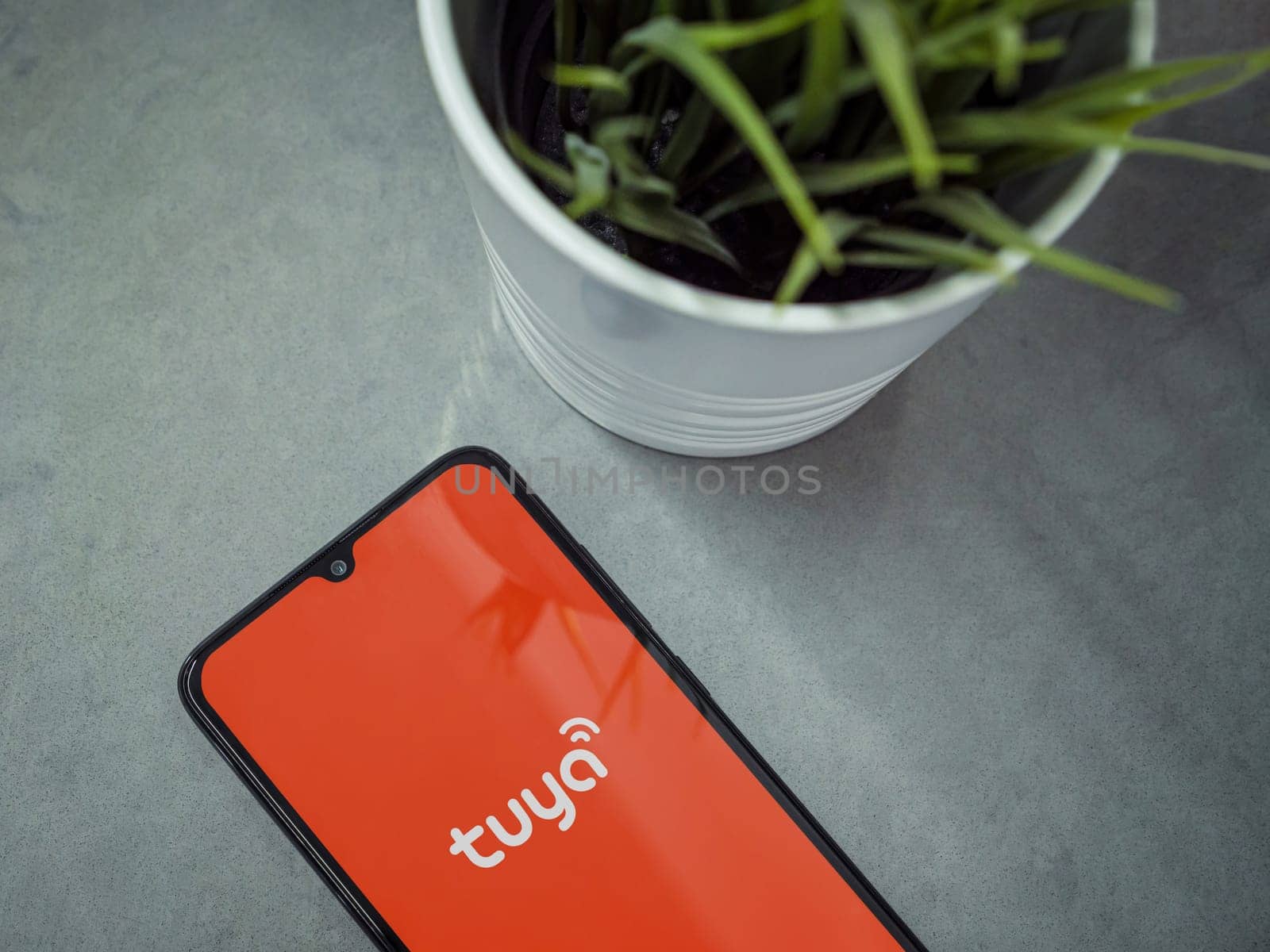 Lod, Israel - July 16,2023: Modern workspace with smartphone with Tuya Smart app launch screen on marble background. Close up top view flat lay.