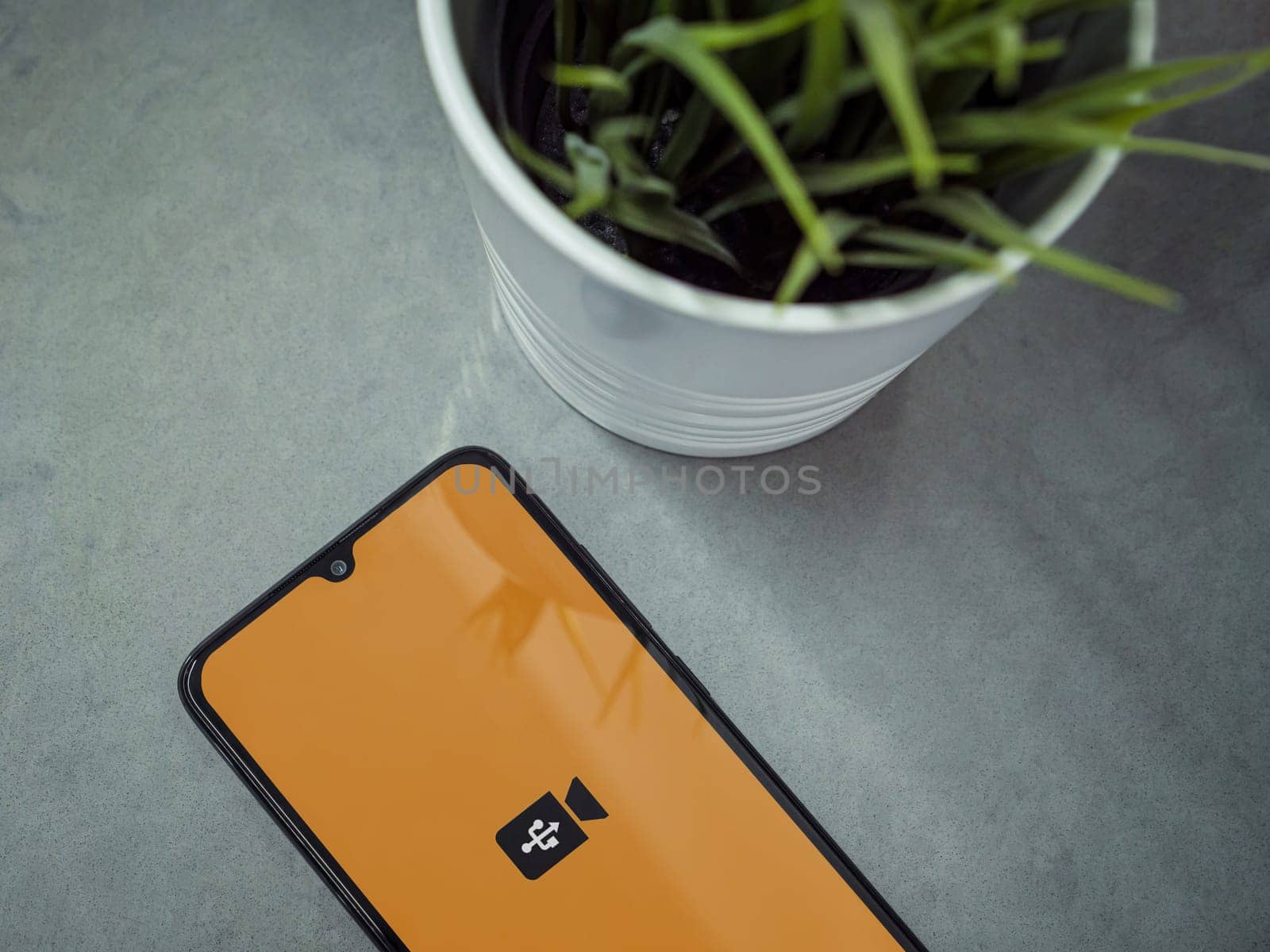 Lod, Israel - July 16,2023: Modern workspace with smartphone with USB Camera app launch screen on marble background. Close up top view flat lay.