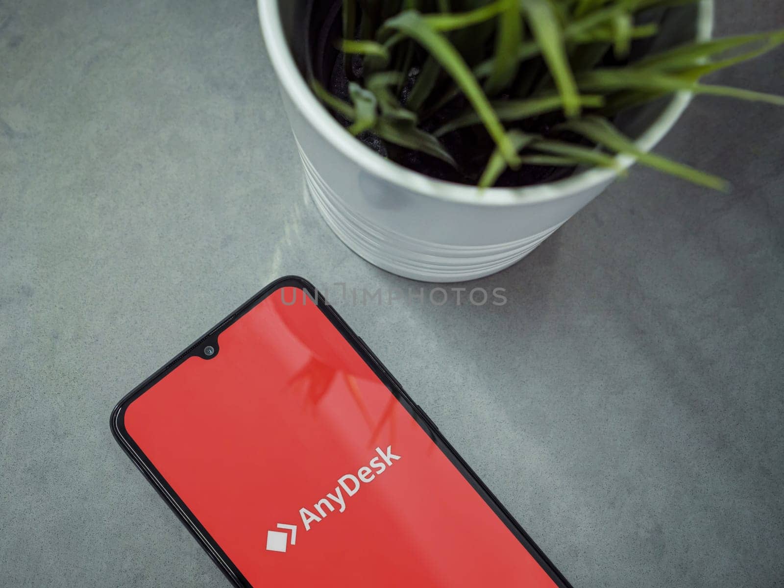 Lod, Israel - July 16,2023: Modern workspace with smartphone with Anydesk app launch screen on marble background. Close up top view flat lay.