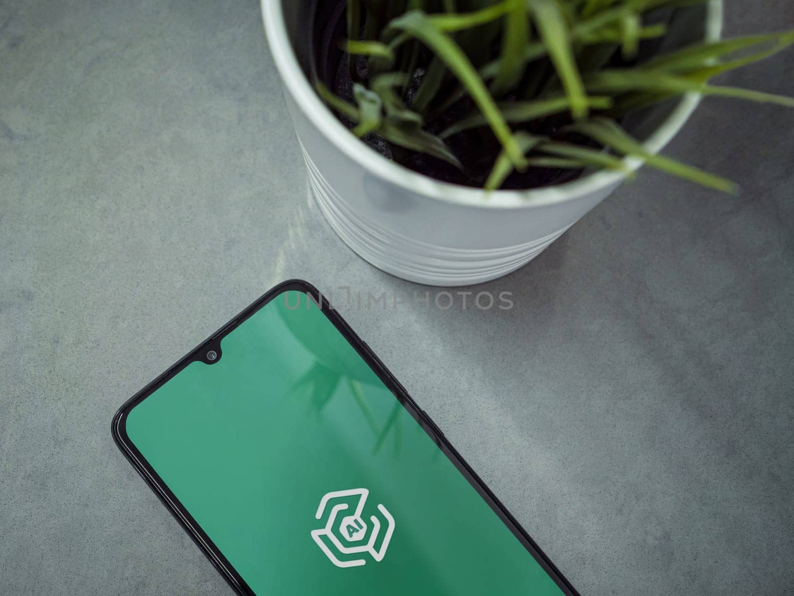 Lod, Israel - July 16,2023: Modern workspace with smartphone with Adam Ai app launch screen on marble background. Close up top view flat lay.