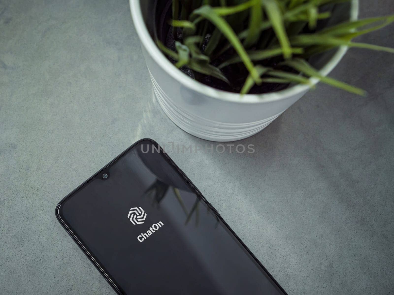 Lod, Israel - July 16,2023: Modern workspace with smartphone with ChatOn app launch screen on marble background. Close up top view flat lay.