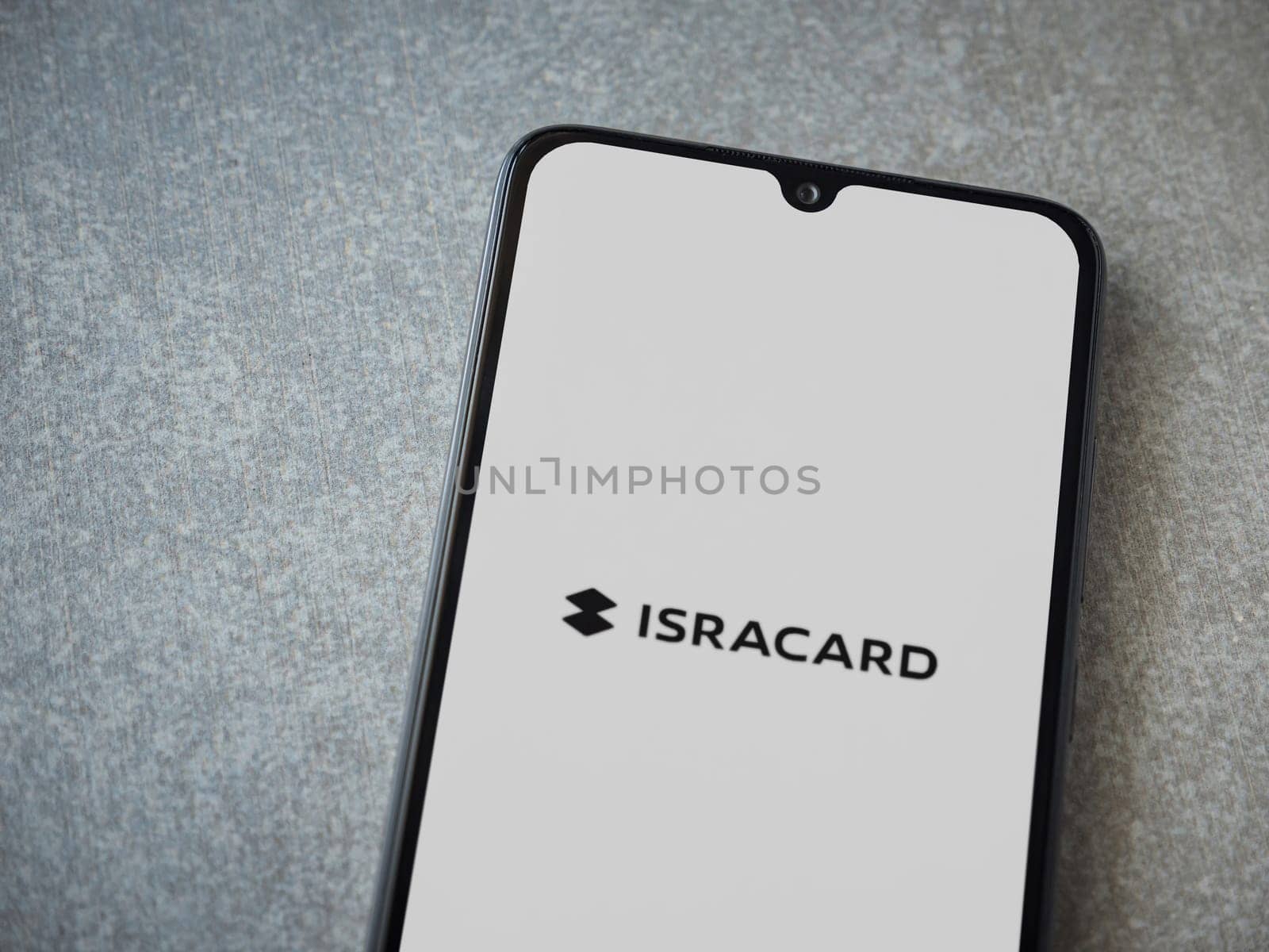 Lod, Israel - July 16,2023: Isracard app launch screen on smartphone on ceramic stone background. Top view flat lay with copy space.