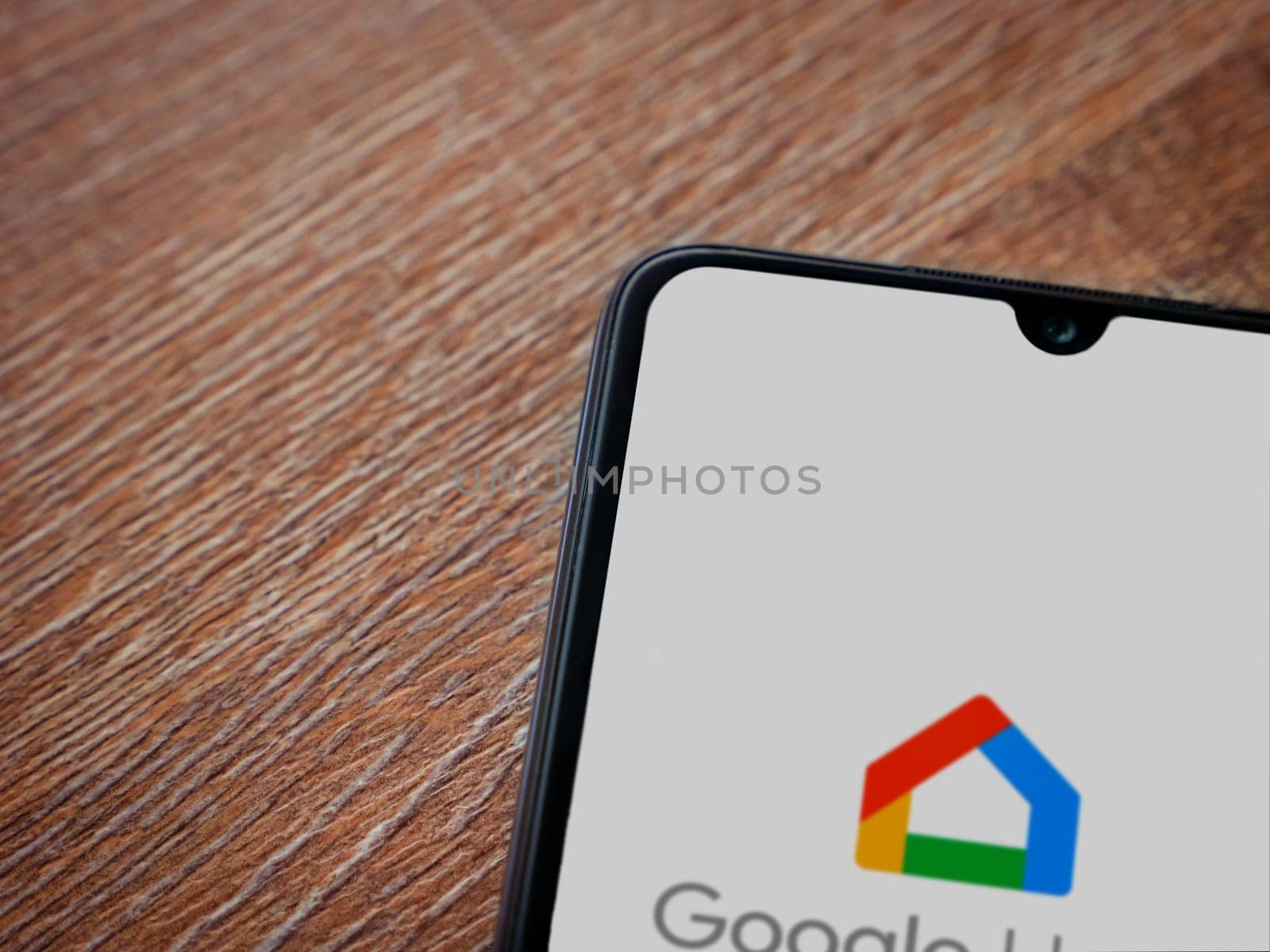 Lod, Israel - July 16,2023: Google Home app launch screen on smartphone on wooden background. Top view flat lay with copy space.