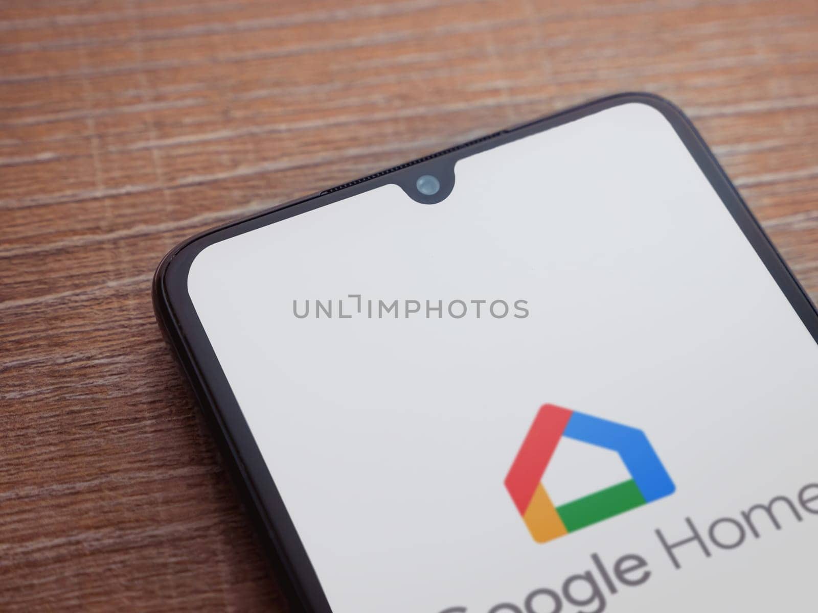 Lod, Israel - July 16,2023: Google Home app launch screen on smartphone on wooden background. Top view flat lay with copy space.