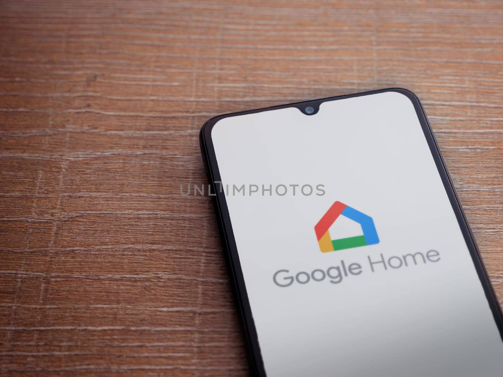 Lod, Israel - July 16,2023: Google Home app launch screen on smartphone on wooden background. Top view flat lay with copy space.