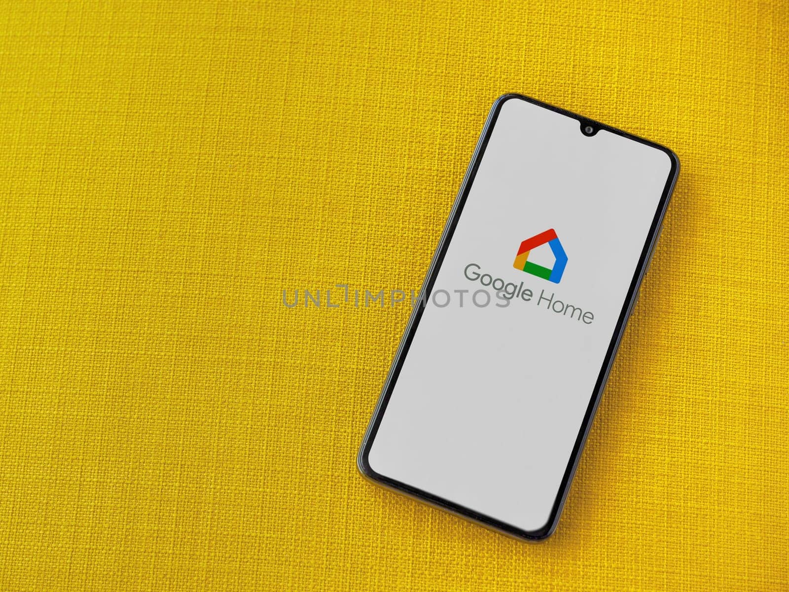 Lod, Israel - July 16,2023: Google Home app launch screen on smartphone on yellow fabric background. Top view flat lay with copy space.