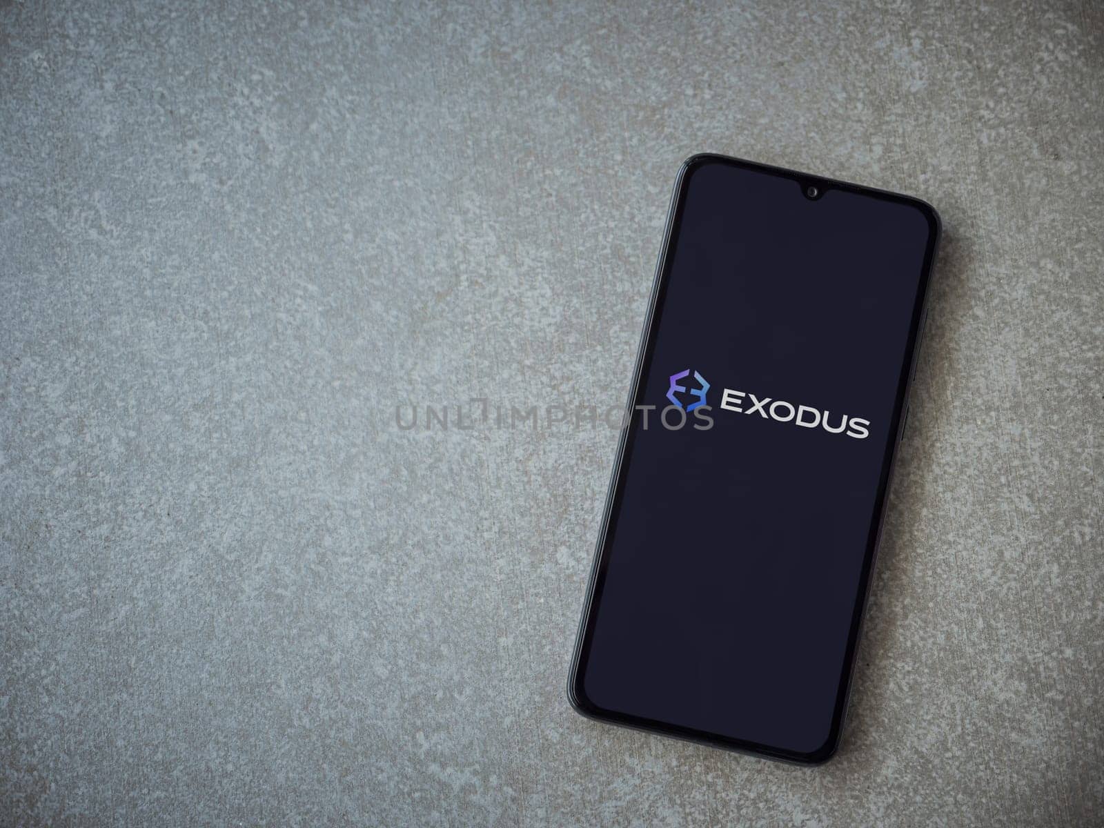 Lod, Israel - July 16,2023: Exodus app launch screen on smartphone on ceramic stone background. Top view flat lay with copy space.