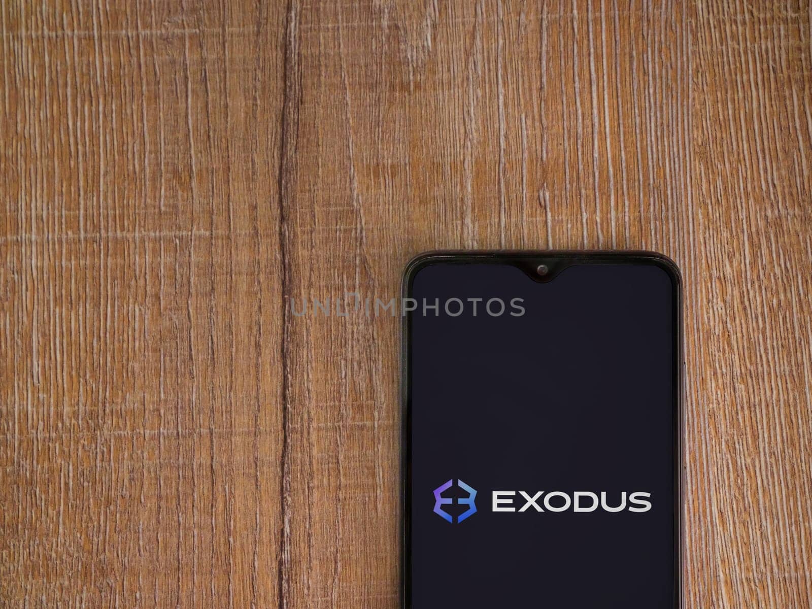 Lod, Israel - July 16,2023: Exodus app launch screen on smartphone on wooden background. Top view flat lay with copy space.