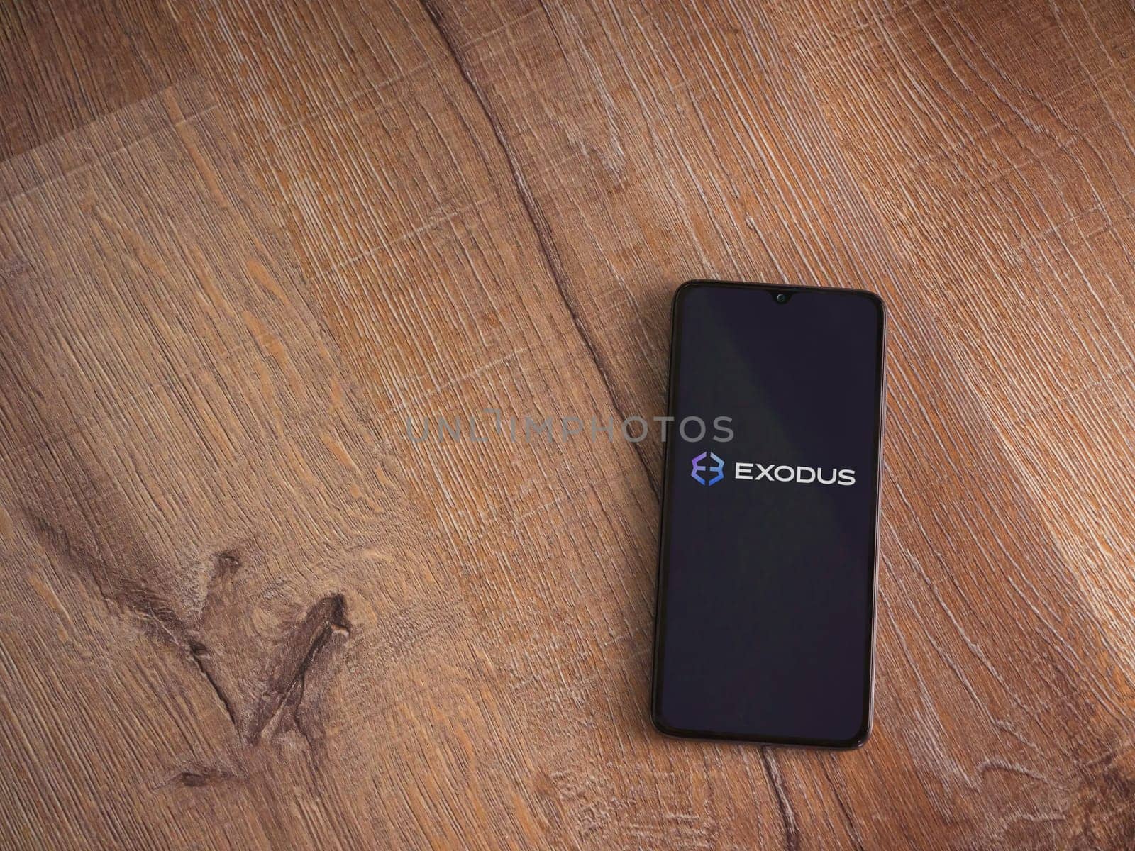 Lod, Israel - July 16,2023: Exodus app launch screen on smartphone on wooden background. Top view flat lay with copy space.