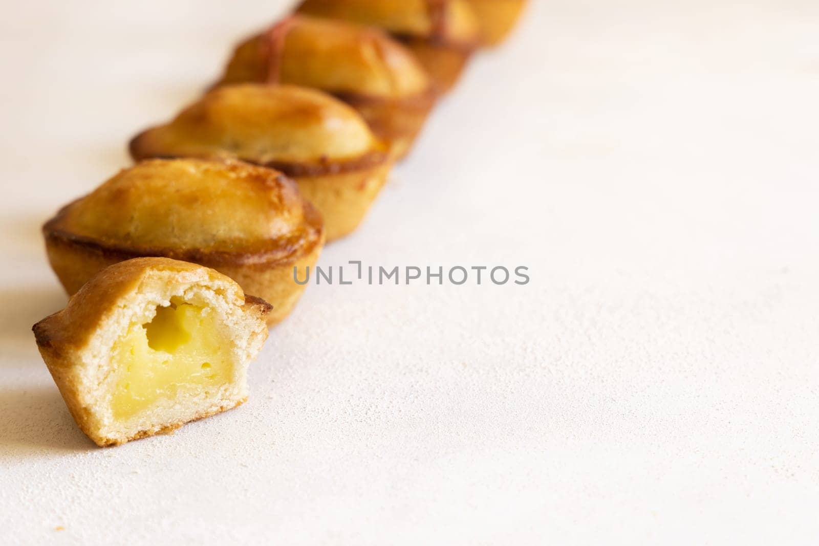Pasticciotto leccese pastry filled with egg custard cream, typical sweet from Lecce, Italy. Pieces of baked pasticiotto on a white table in a line, apulian breakfast, close up