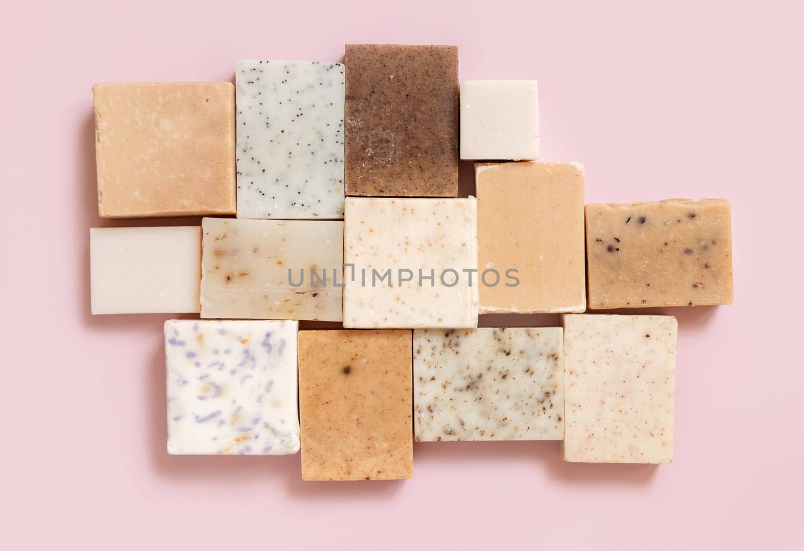 Beige and brown handmade soap bars on light pink top view, copy space. Natural herbal products for Spa and skin care. Using organic handmade skincare products in everyday routine