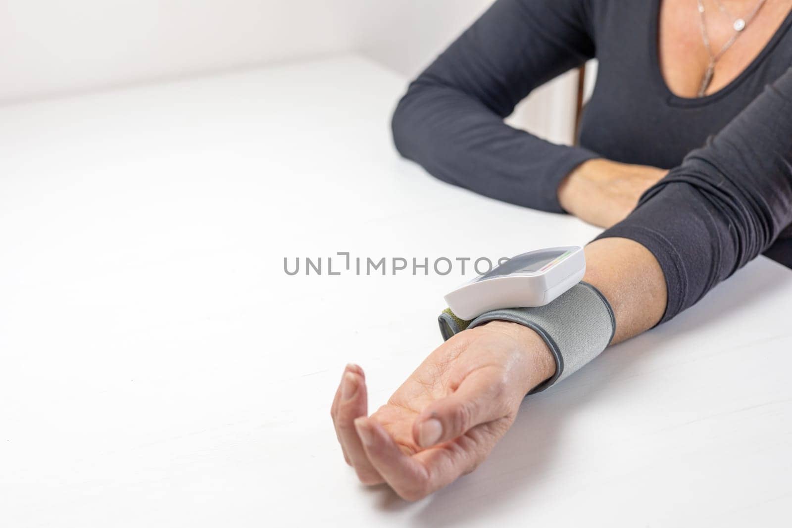Woman is measuring her own blood pressure at home. There is enough space for your text on the photo.