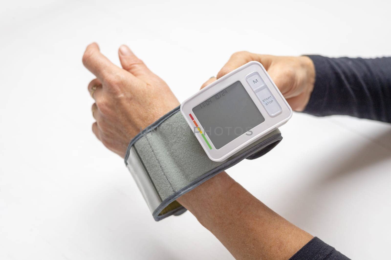 Woman is putting Blood Pressure Monitor on her hand. Horizontally.