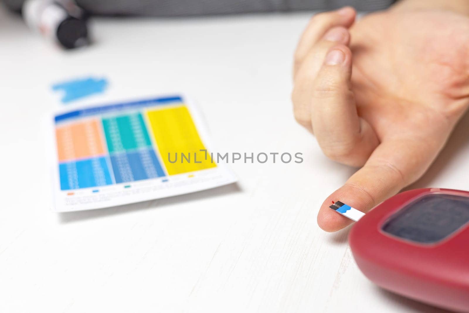 Home health prevention. Male hand with a drop of blood on his finger uses a glucometer strip. Horizontally.