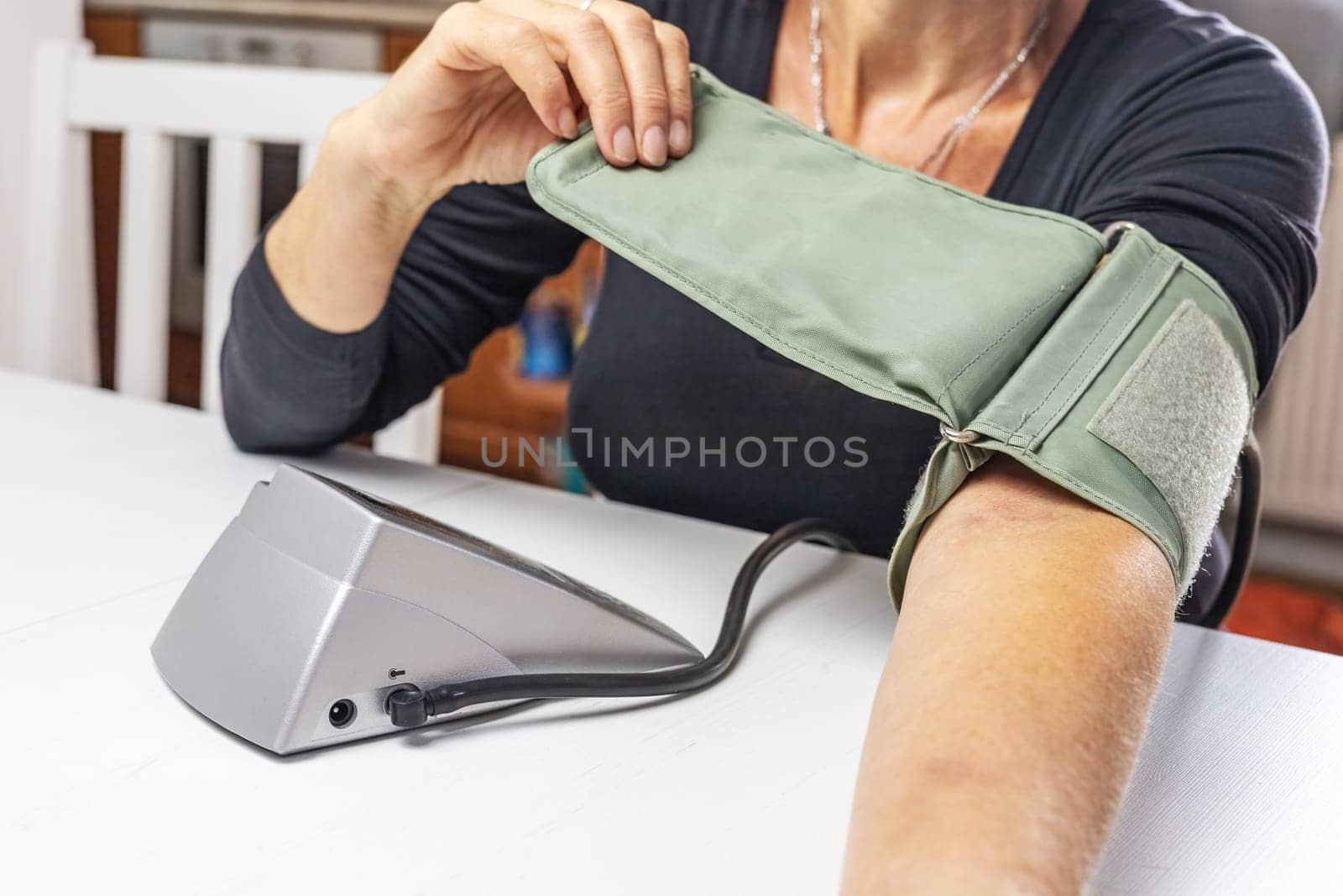 Woman is preparing older type of Blood Pressure Monitor on her hand. Horizontally.