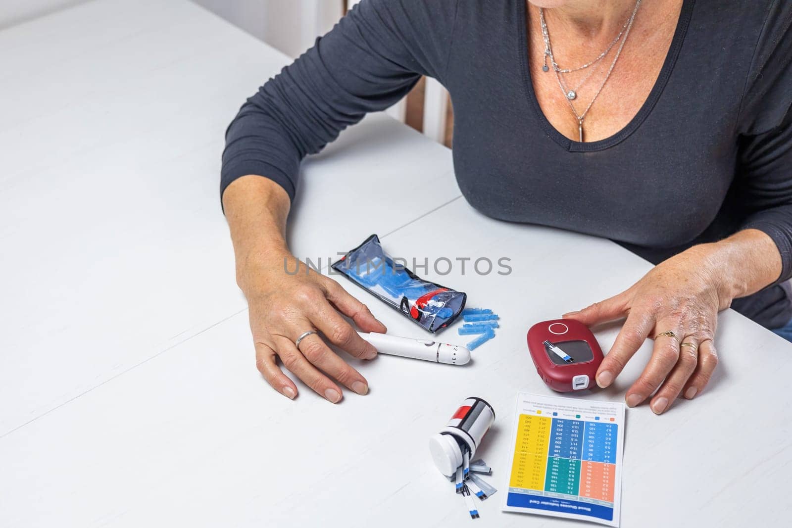 Top view of woman preparing device for measuring blood sugar on the white table.