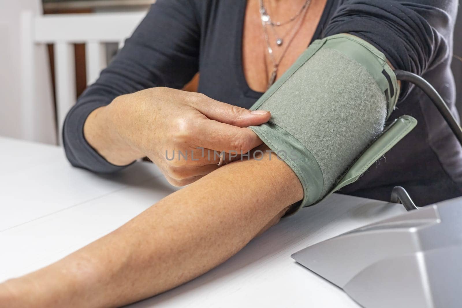 Woman is showing the correct use of a older type blood pressure monitor.