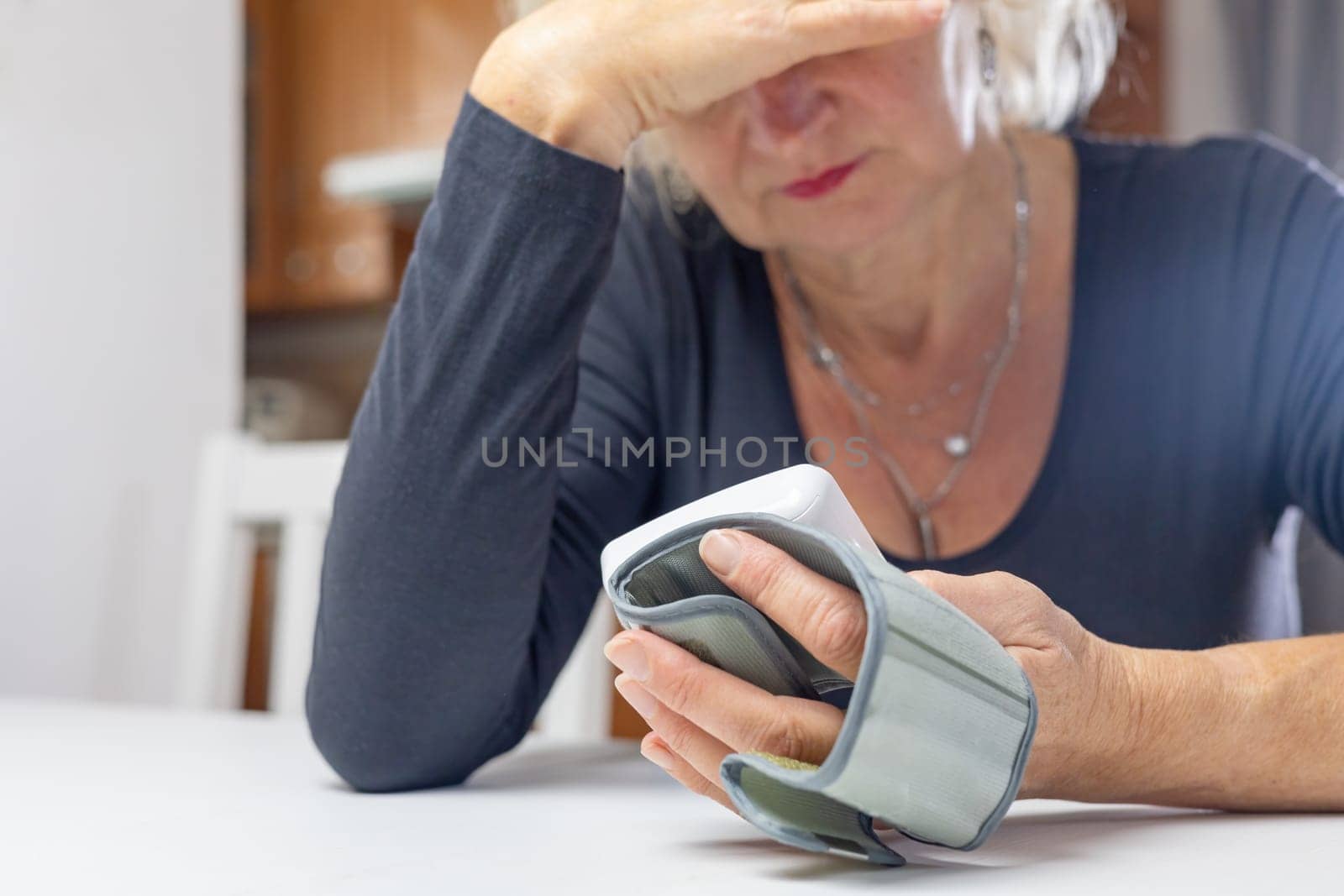 Woman lis looking at the results of blood pressure measurement with her hand on her forehead.