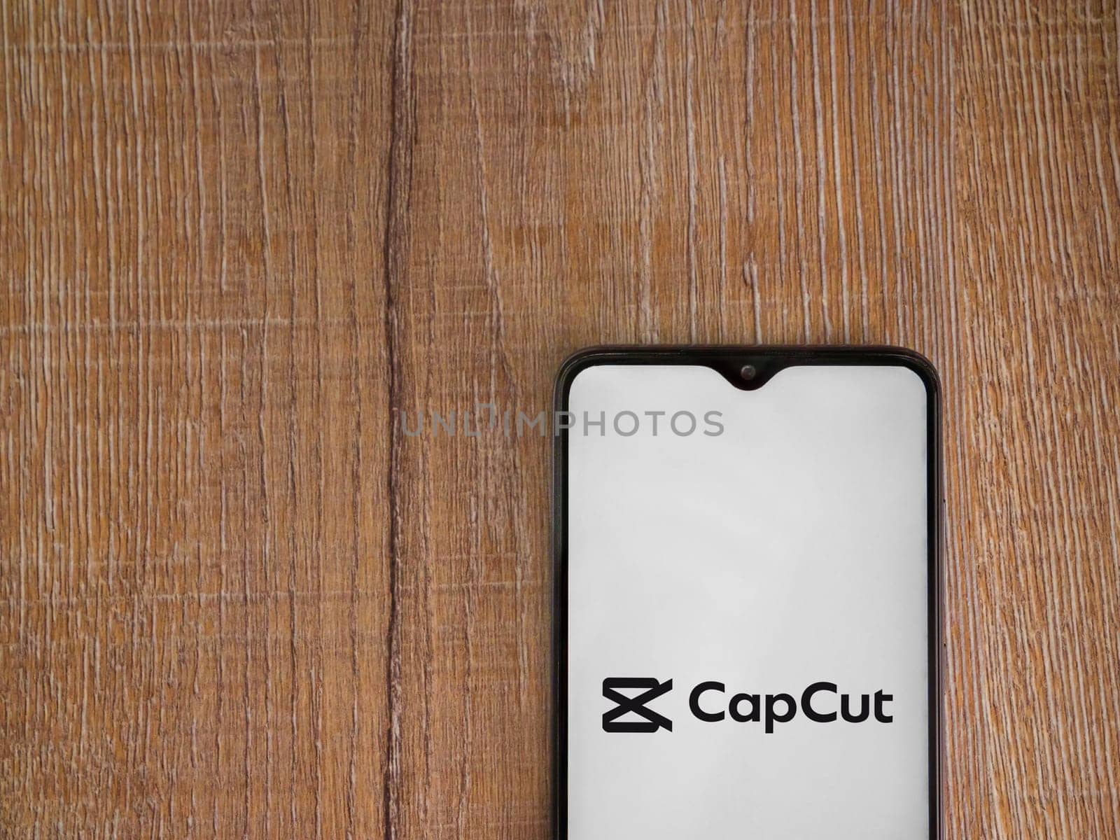 Lod, Israel - July 16,2023: CapCut app launch screen on smartphone on wooden background.. Top view flat lay with copy space.