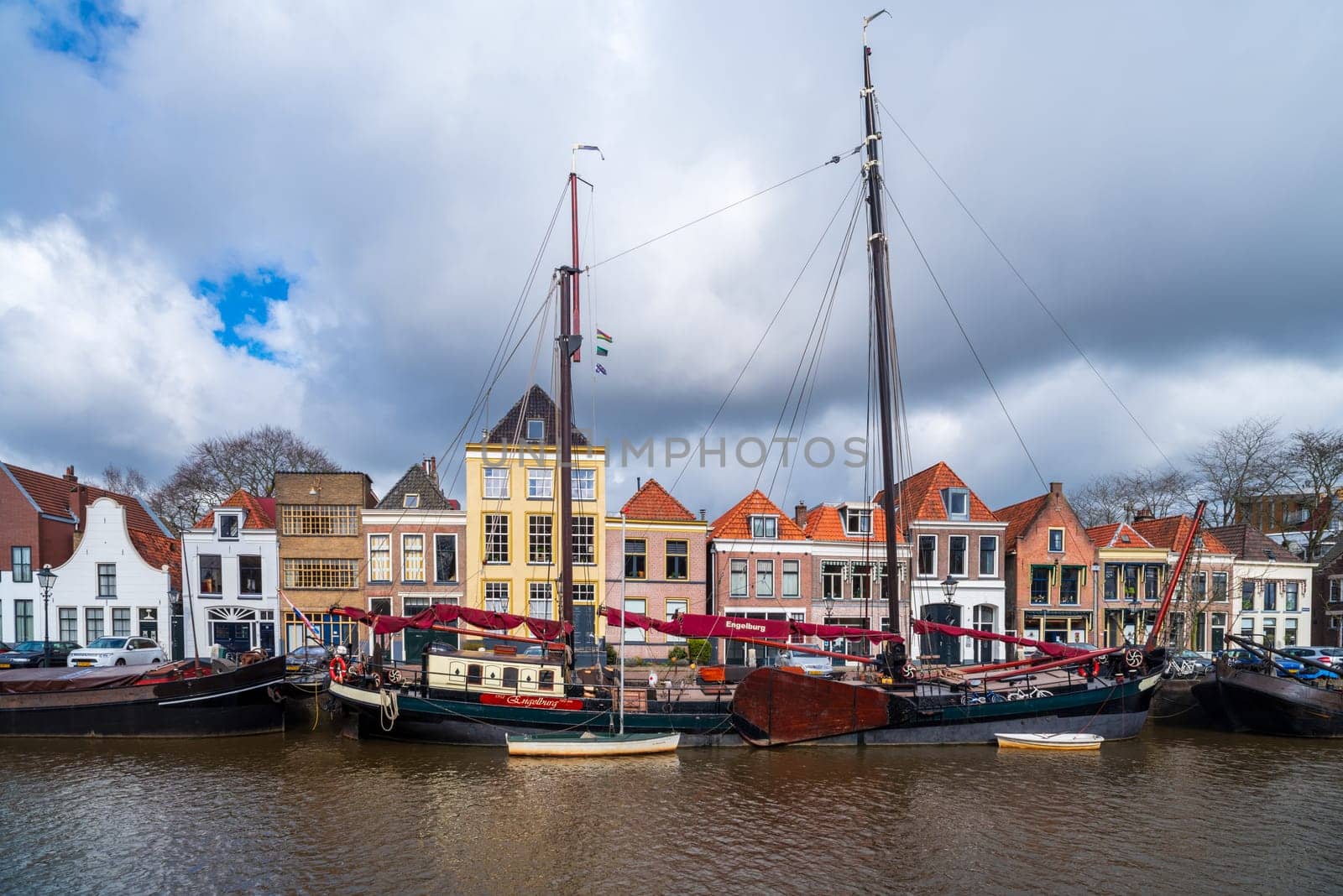 ZWOLLE, NETHERLANDS - MARCH 14, 2021: Old boats and barges in front of some nice gabled houses in the dutch city of Zwolle