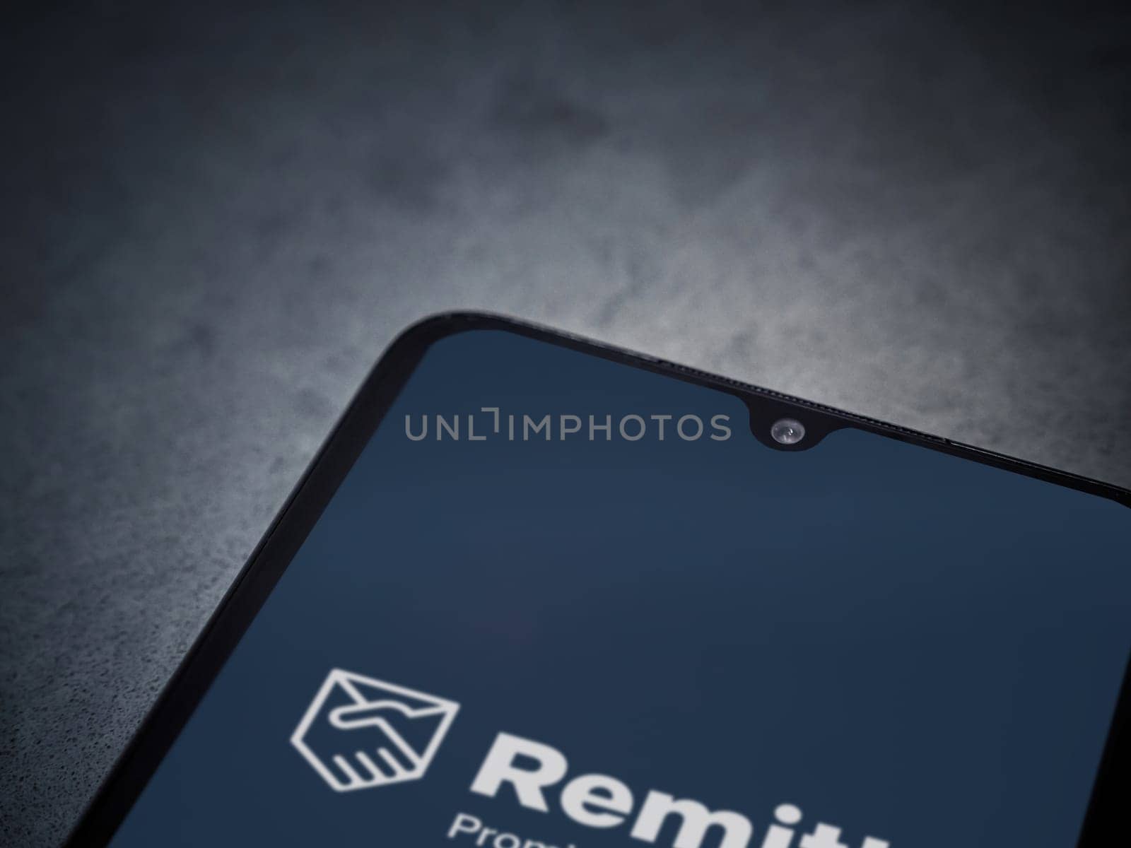 Lod, Israel - July 16,2023: Remitly app launch screen on smartphone on dark marble stone background. Top view flat lay with copy space.