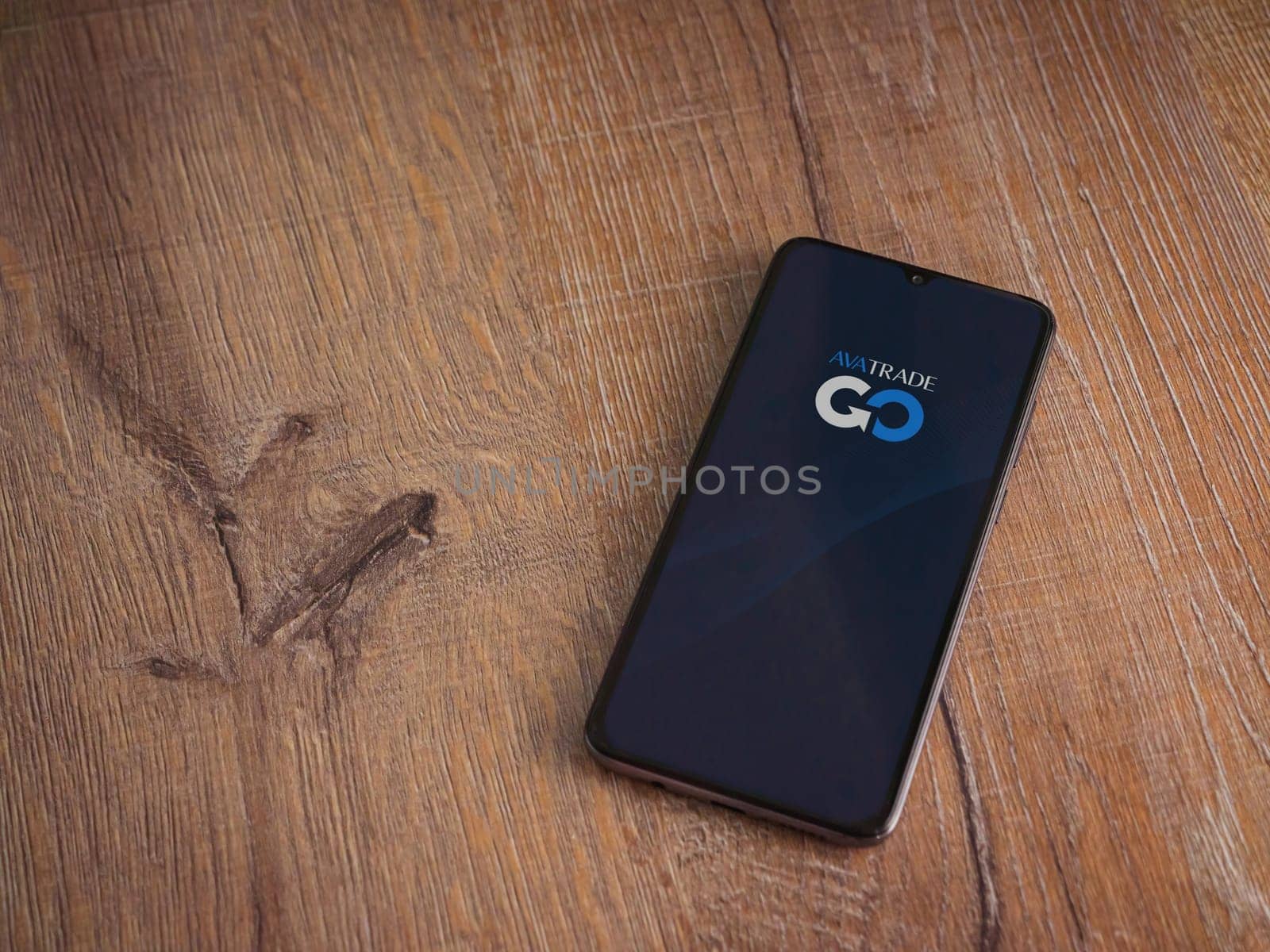 Lod, Israel - July 16,2023: Avatrade app launch screen on smartphone on wooden background. Top view flat lay with copy space.