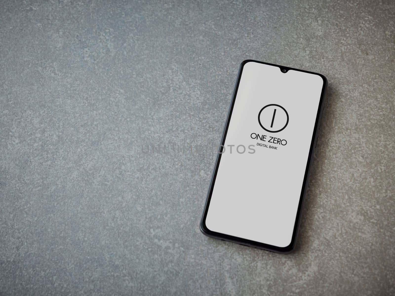 Lod, Israel - July 16,2023: One Zero app launch screen on smartphone on ceramic stone background. Top view flat lay with copy space.