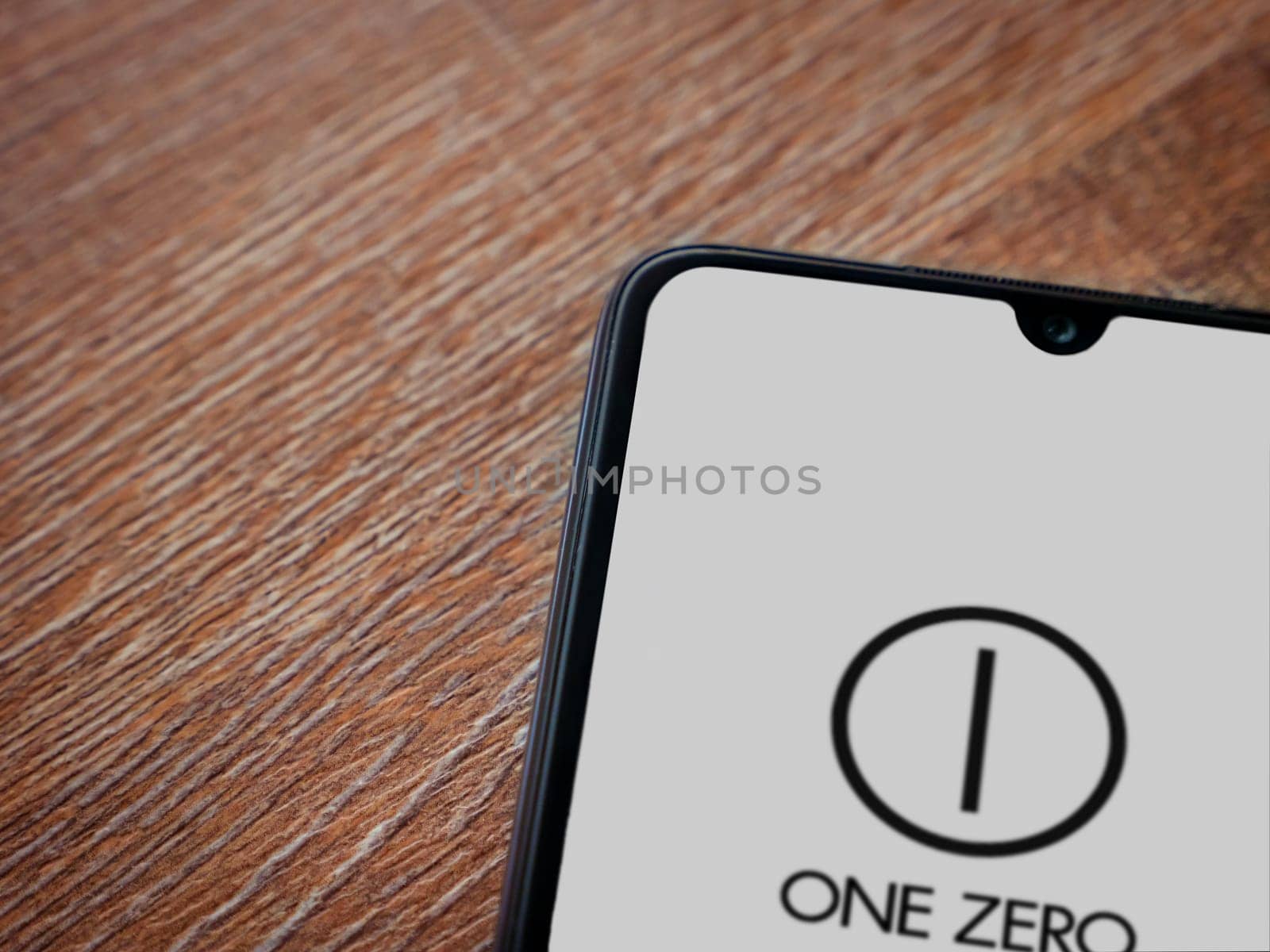 Lod, Israel - July 16,2023: One Zero app launch screen on smartphone on wooden background. Top view flat lay with copy space.