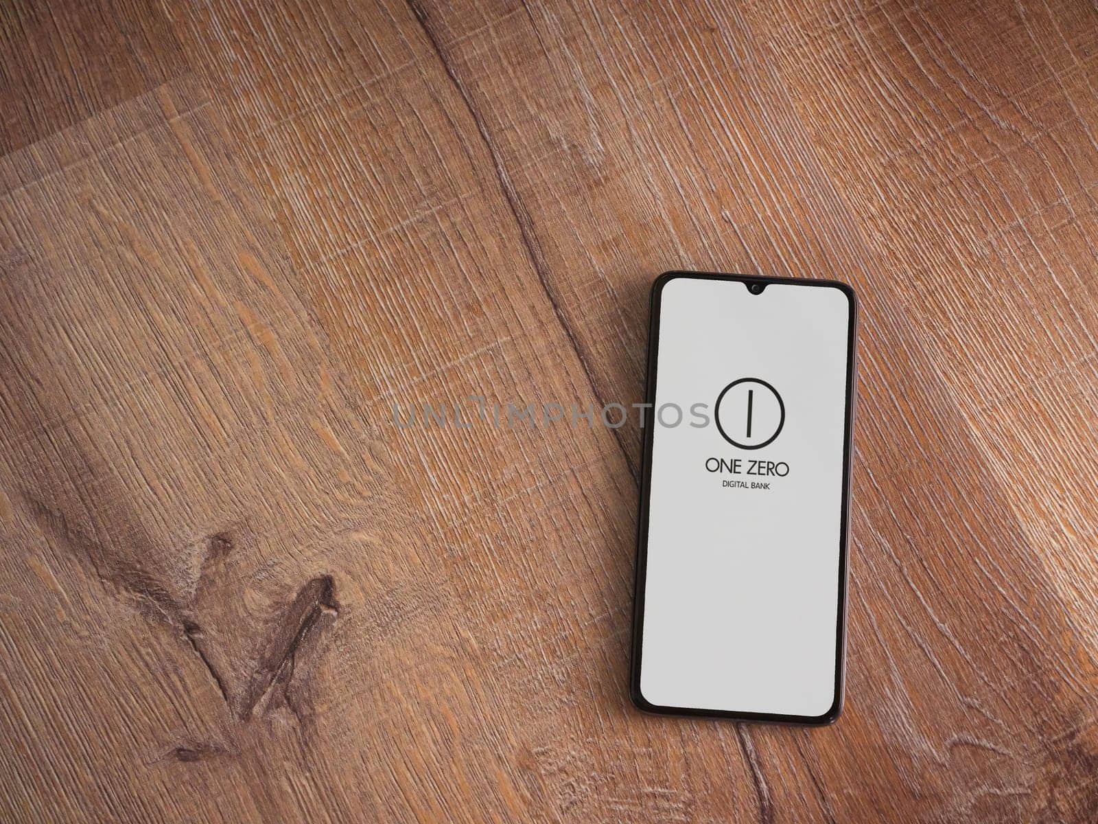 Lod, Israel - July 16,2023: One Zero app launch screen on smartphone on wooden background. Top view flat lay with copy space.