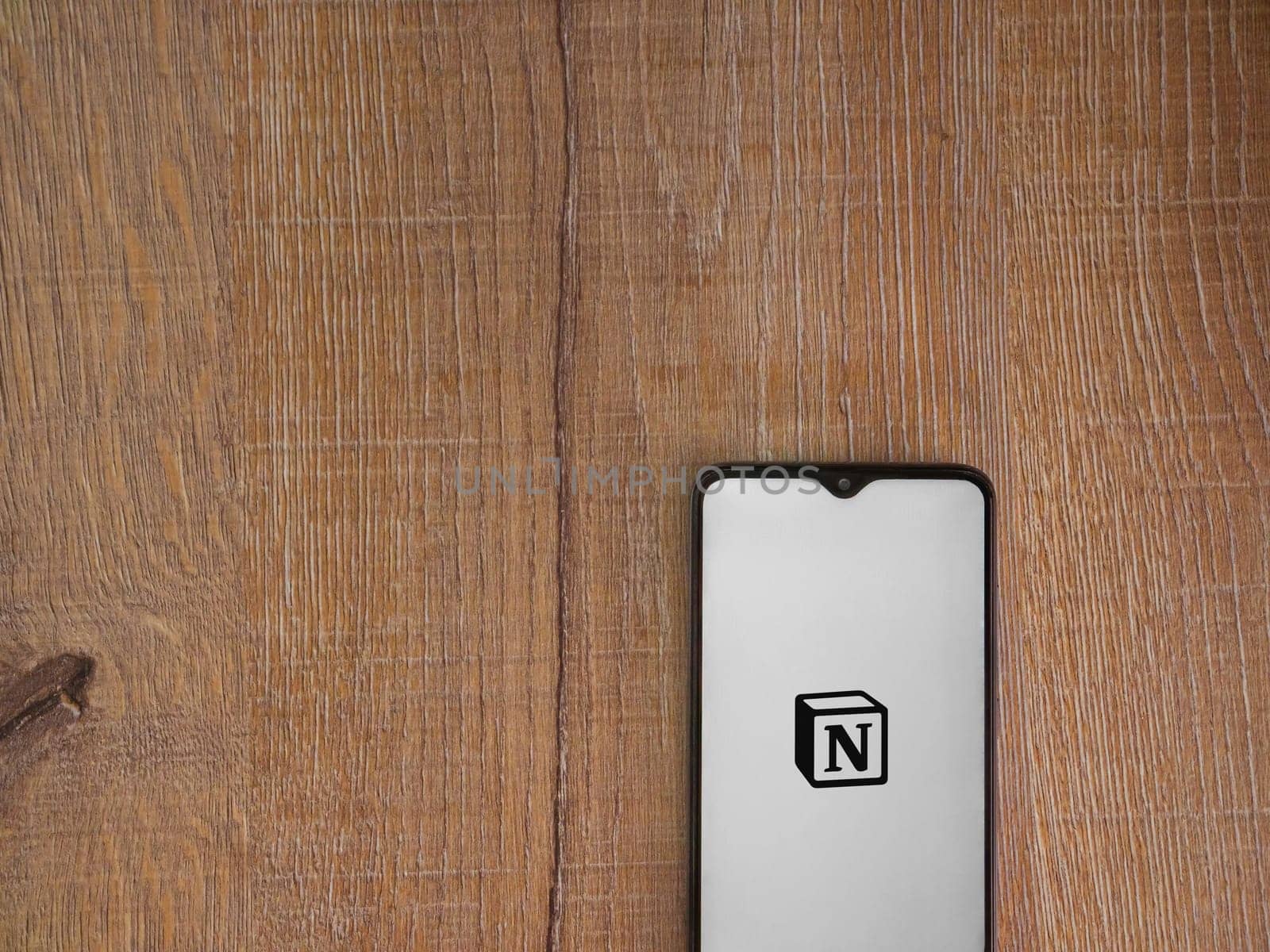 Lod, Israel - July 16,2023: Notion app launch screen on smartphone on wooden background. Top view flat lay with copy space.
