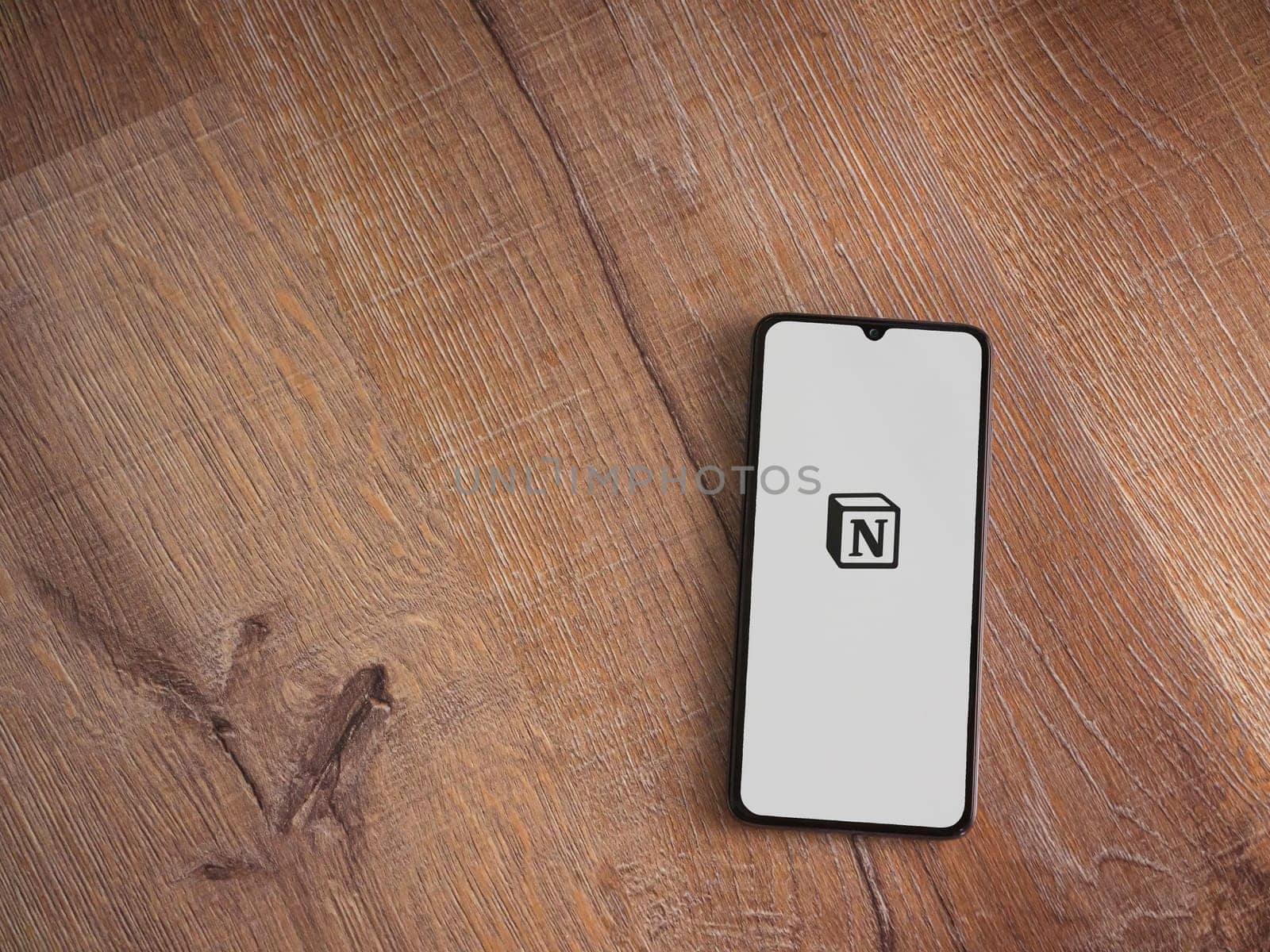 Lod, Israel - July 16,2023: Notion app launch screen on smartphone on wooden background. Top view flat lay with copy space.