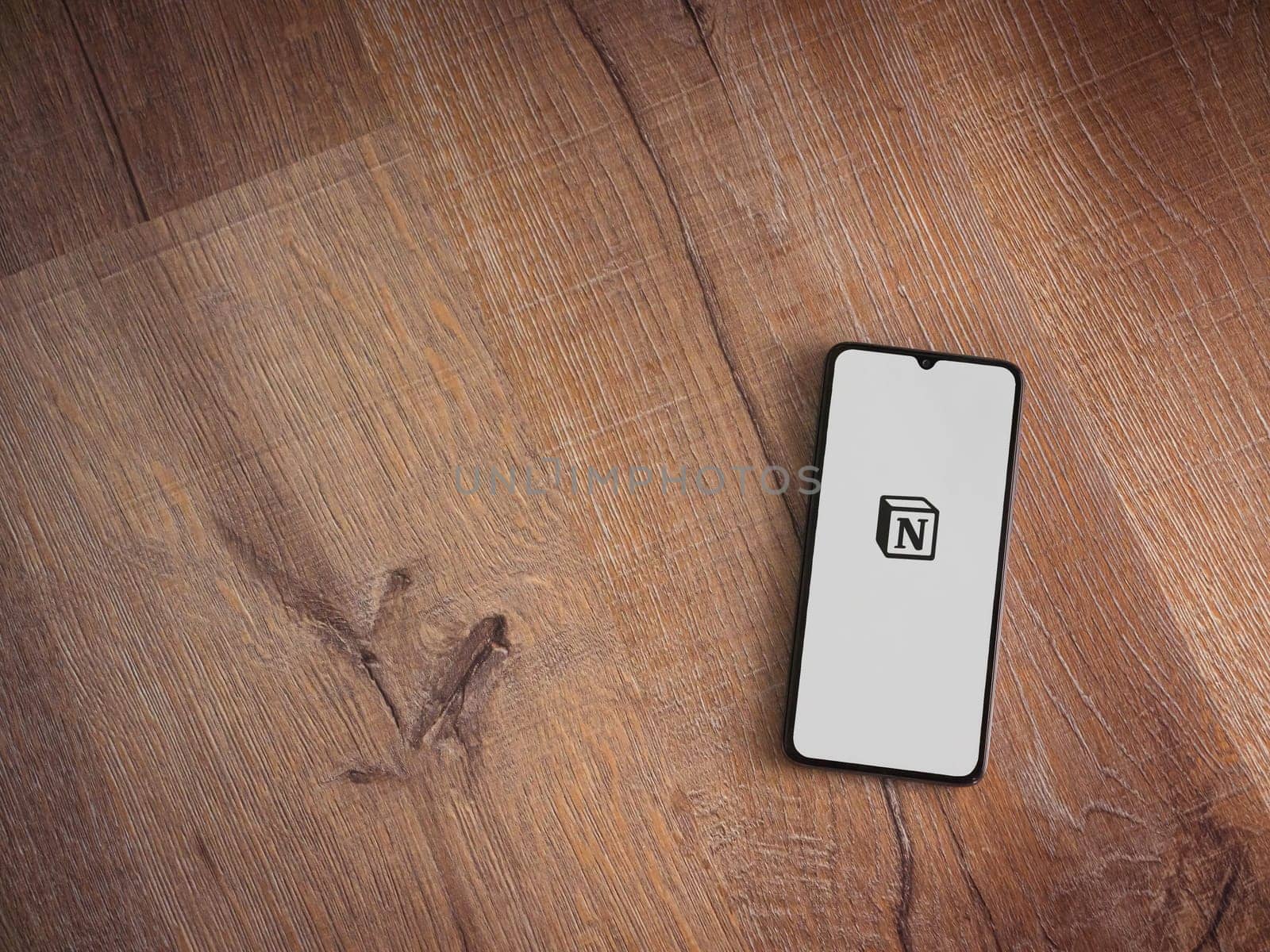 Lod, Israel - July 16,2023: Notion app launch screen on smartphone on wooden background. Top view flat lay with copy space.