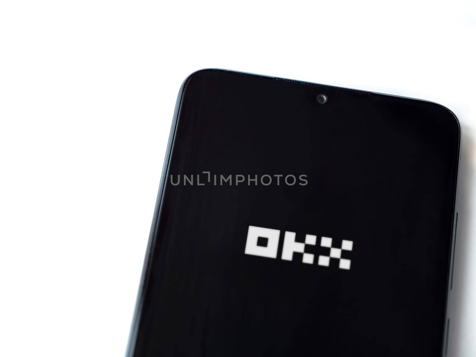 Lod, Israel - July 16,2023: OKX app launch screen on smartphone on white background. Top view flat lay with copy space.
