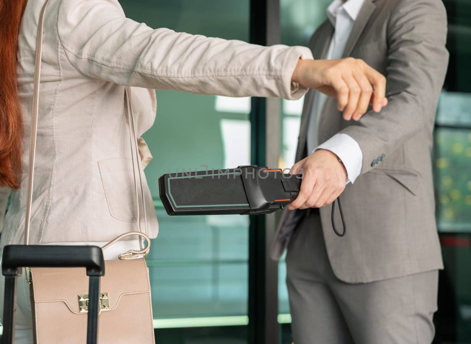 Security male officer using metal detector on female passenger at airport boarding gate. Airport travel and security concept.
