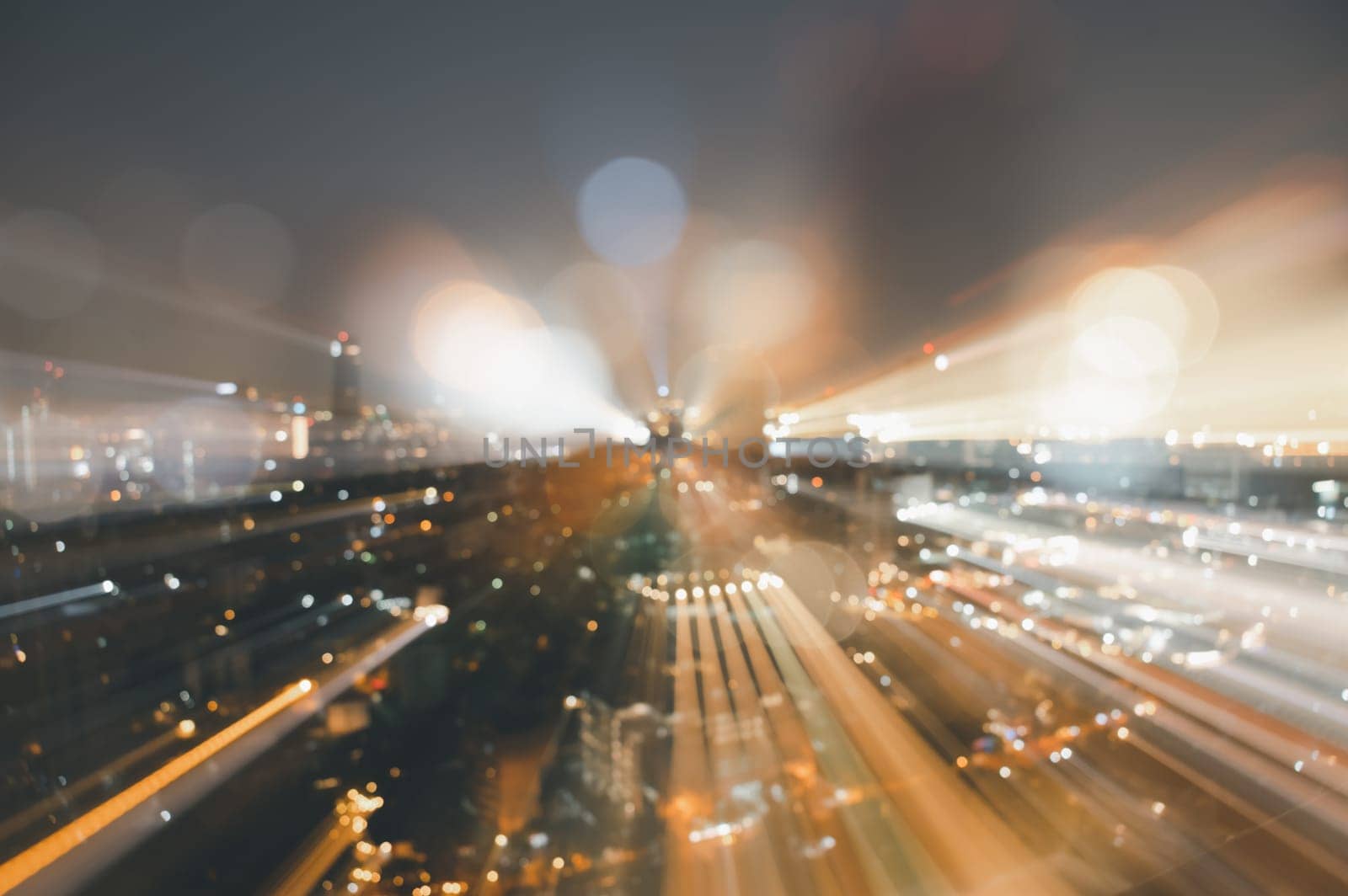 Blurred abstract background of skyscrapers at night with bokeh lights trail using zoom technique.
