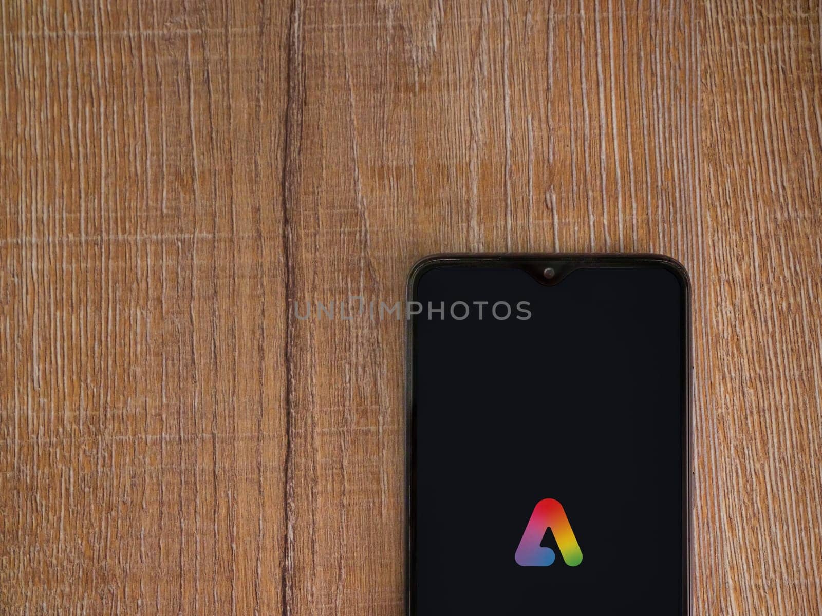 Lod, Israel - July 16,2023: Adobe Express - Graphic Design app launch screen on smartphone on wooden background.. Top view flat lay with copy space.