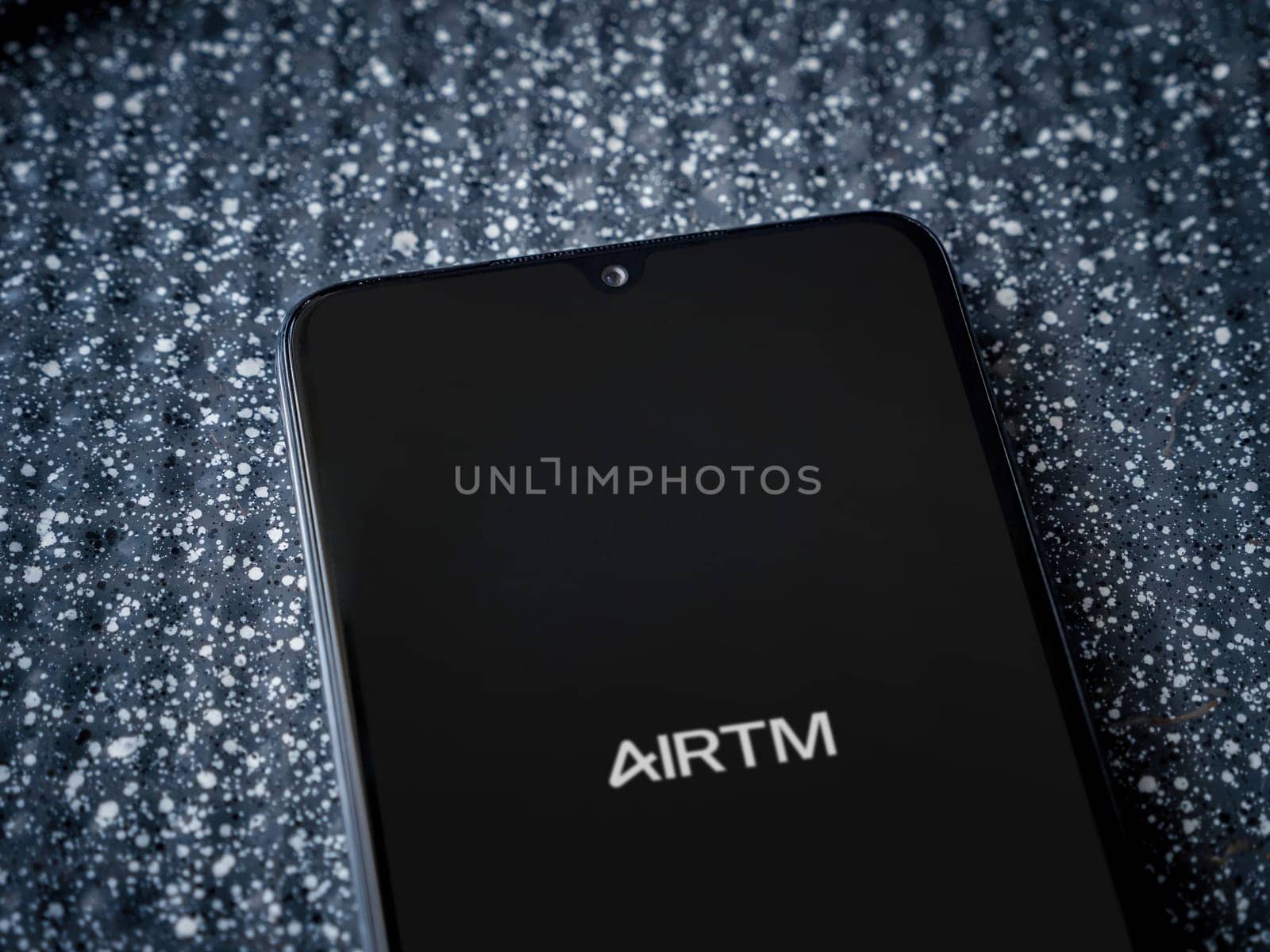 Lod, Israel - July 16,2023: AirTM app launch screen on smartphone on metallic background. Close up top view flat lay.
