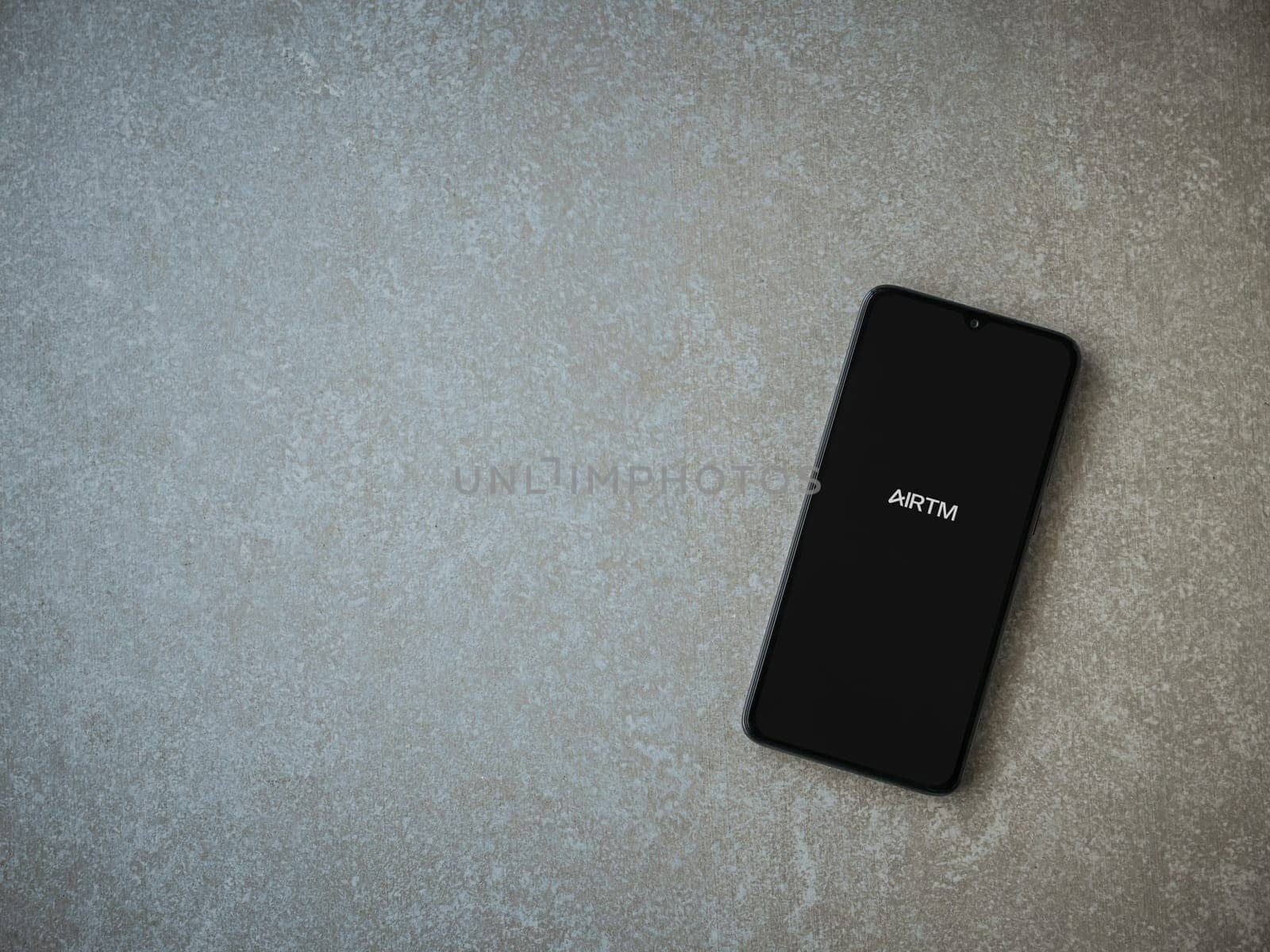 Lod, Israel - July 16,2023: AirTM app launch screen on smartphone on ceramic stone background. Top view flat lay with copy space.