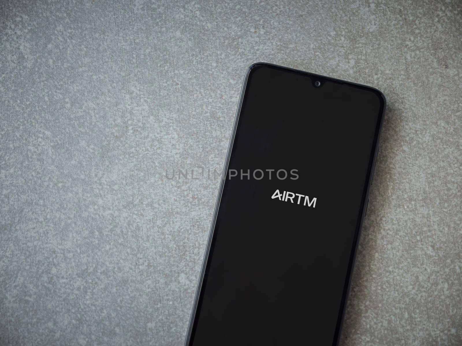 Lod, Israel - July 16,2023: AirTM app launch screen on smartphone on ceramic stone background. Top view flat lay with copy space.