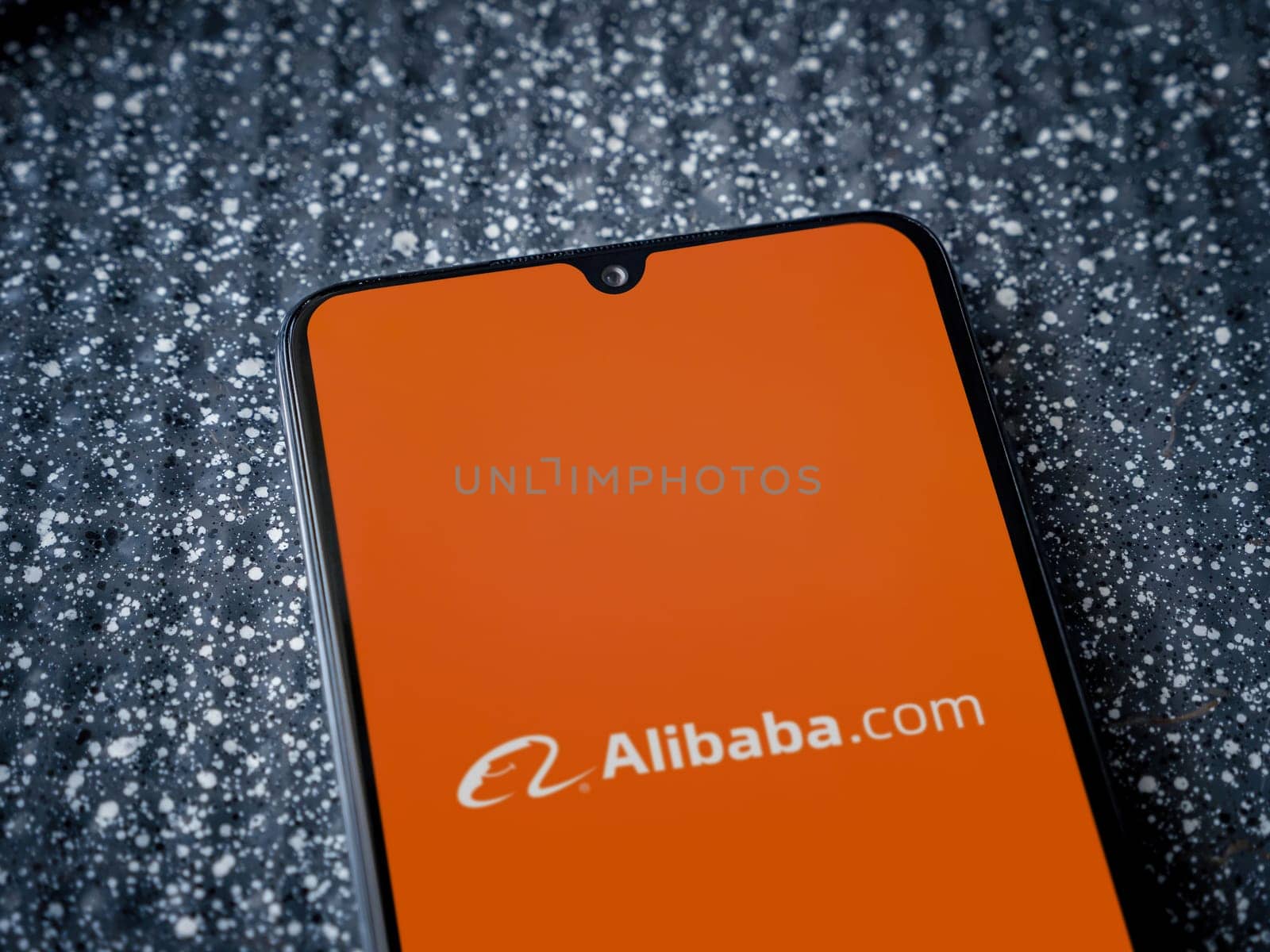 Lod, Israel - July 16,2023: Alibaba.com app launch screen on smartphone on metallic background. Close up top view flat lay.