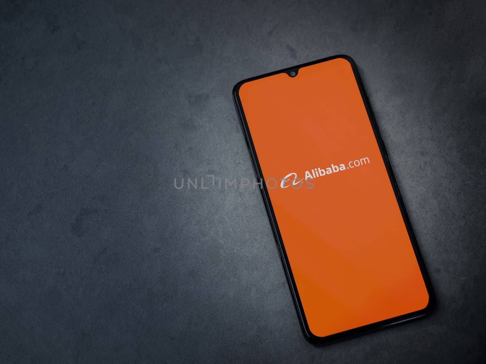 Lod, Israel - July 16,2023: Alibaba.com app launch screen on smartphone on dark marble stone background. Top view flat lay with copy space.