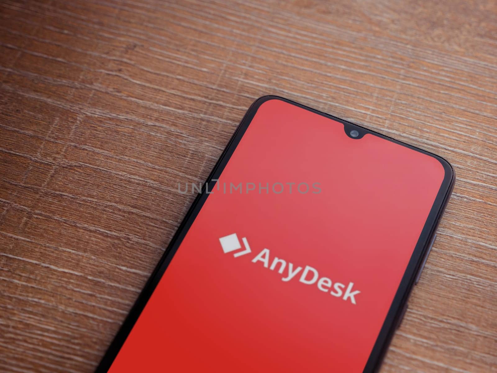 Lod, Israel - July 16,2023: Anydesk app launch screen on smartphone on wooden background. Top view flat lay with copy space.